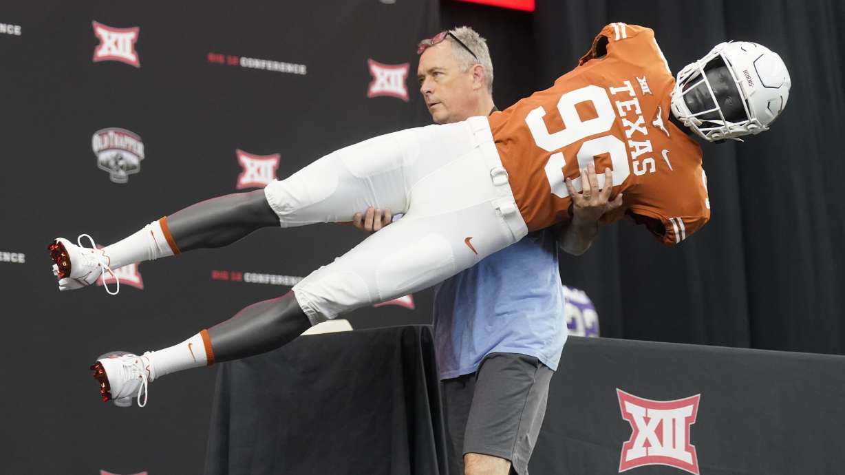 Brad Clements carries off a mannequin wearing a Texas football uniform as he dismantles the stage after the NCAA college football Big 12 media days in Arlington, Texas, Thursday, July 14, 2022.
