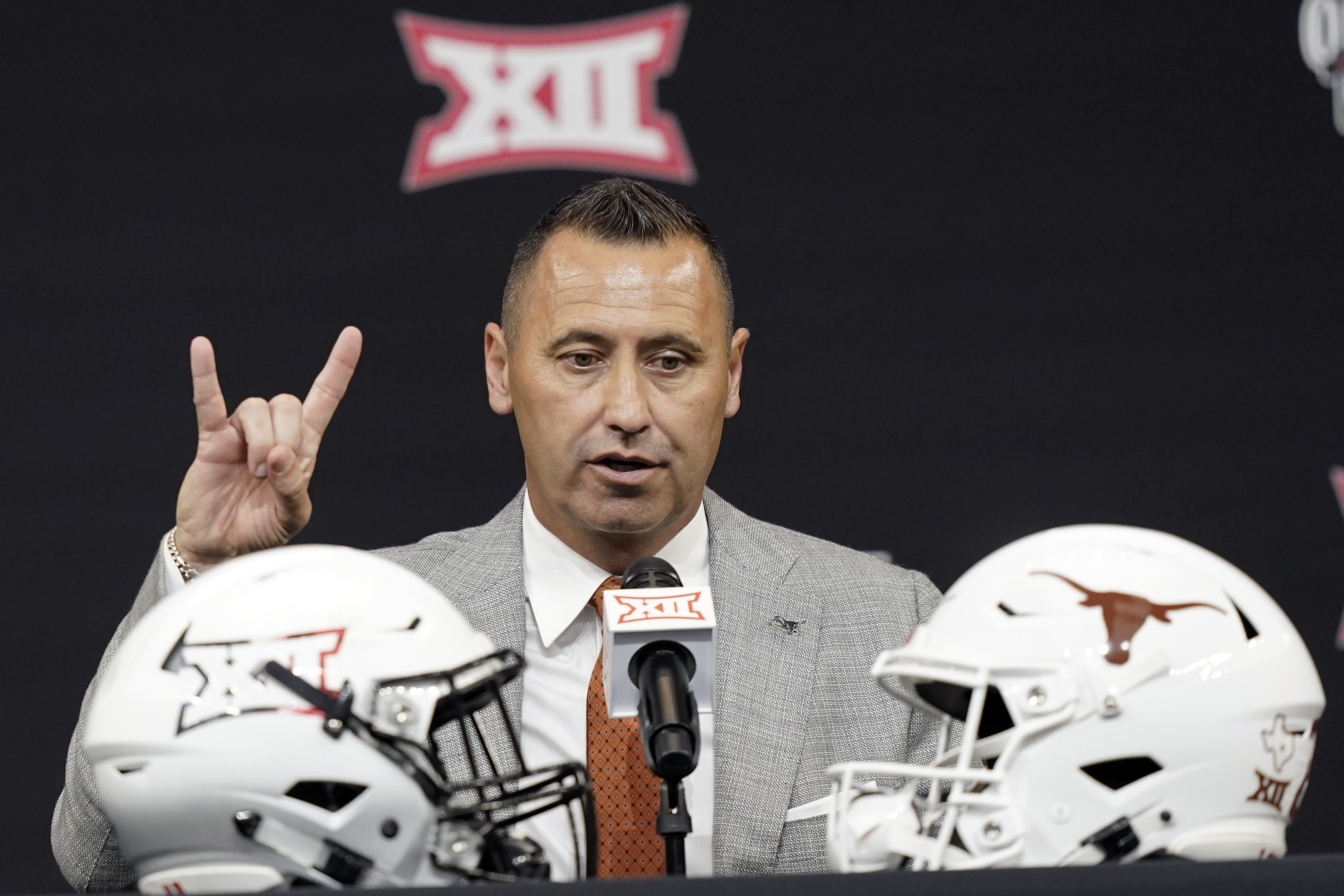 Texas head coach Steve Sarkisian flashes a quick Hook 'em Horns sign as finishes up speaking to reporters at the NCAA college football Big 12 media days in Arlington, Texas, Thursday, July 14, 2022.