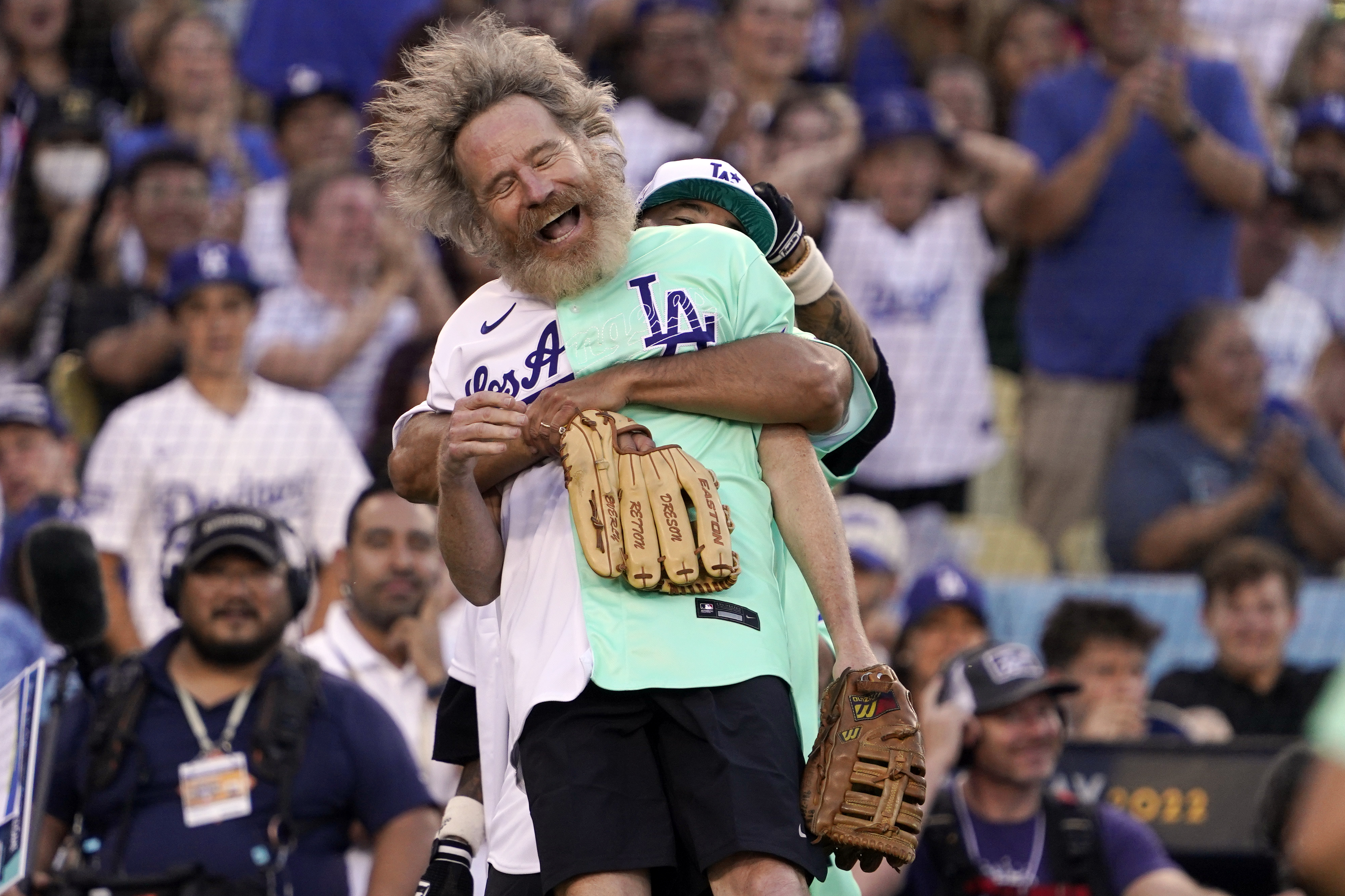 Actor Bryan Cranston is lifted by former Los Angeles Dodgers player Andre Ethier during the MLB All Star Celebrity Softball game, Saturday, July 16, 2022, in Los Angeles. 