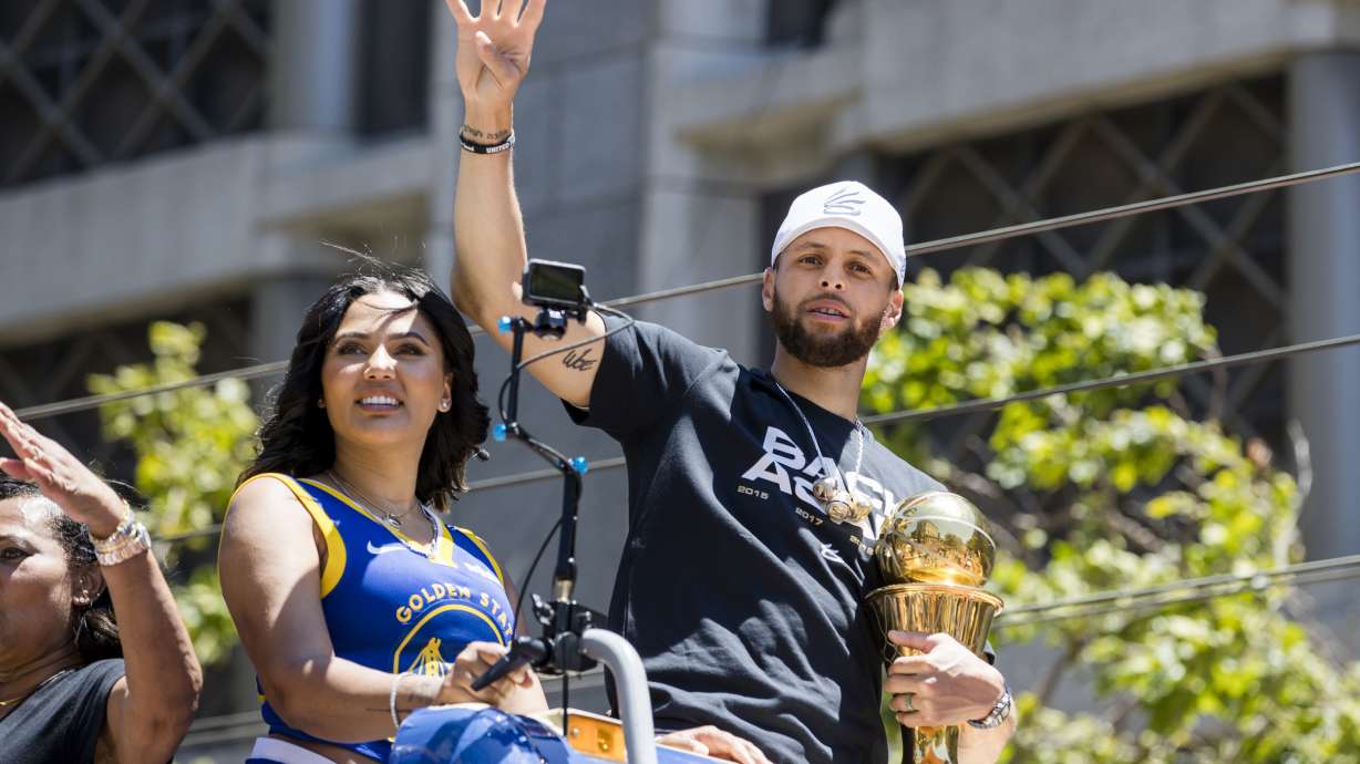 Golden State Warriors' Stephen Curry accompanied by his wife Ayesha, left, holds the Larry O'Brien trophy during the NBA Championship parade in San Francisco, Monday, June 20, 2022, in San Francisco.