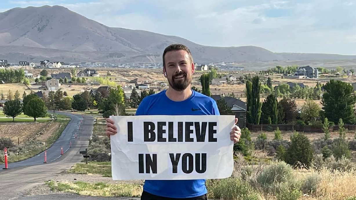 Ben Lyne, of Eagle Mountain, holds his "I believe in you" sign that he carries while he runs.