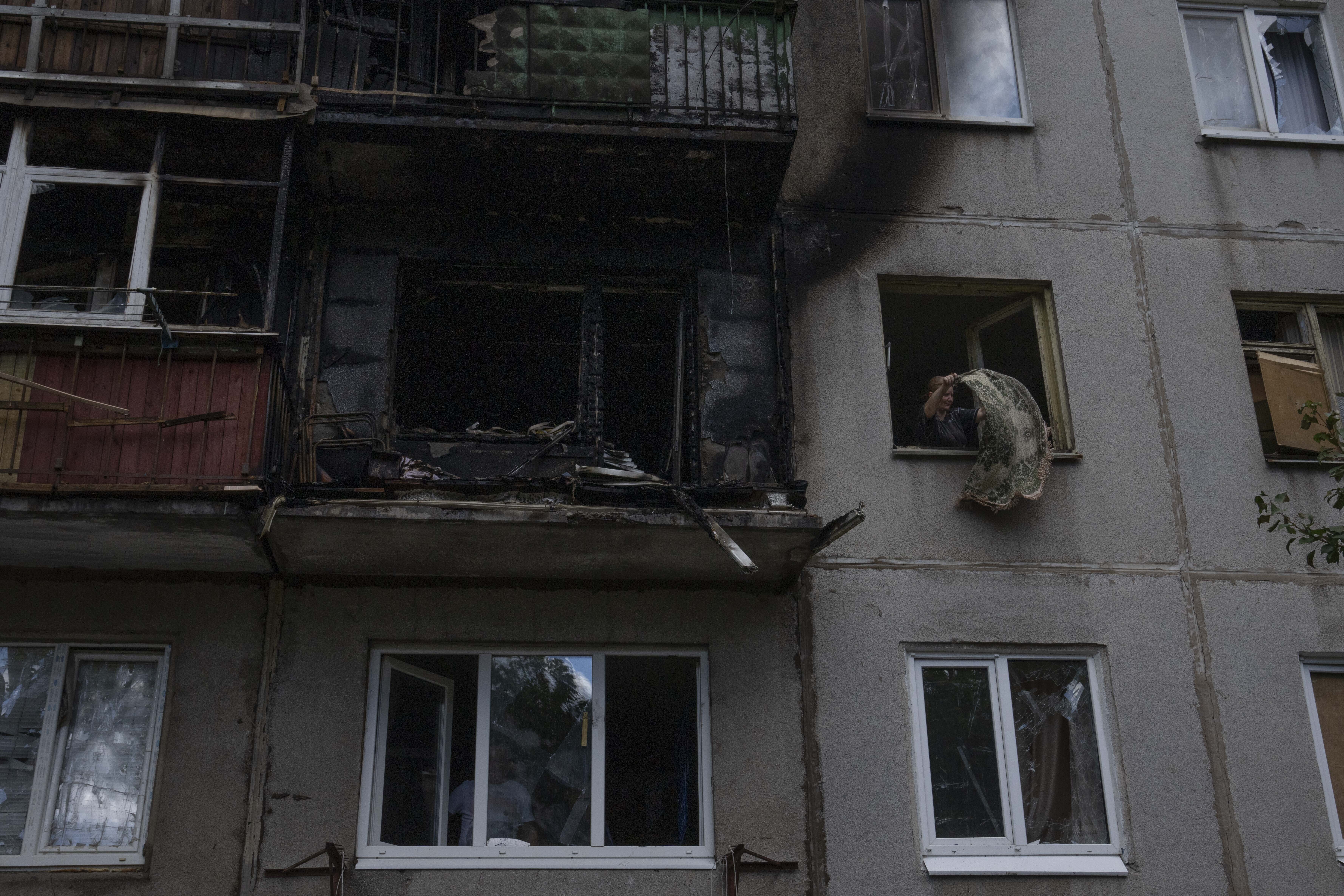 A woman salvages what she can from her damaged apartment, after a rocket hit her five-story residential building, in Kramatorsk, eastern Ukraine, Tuesday.
