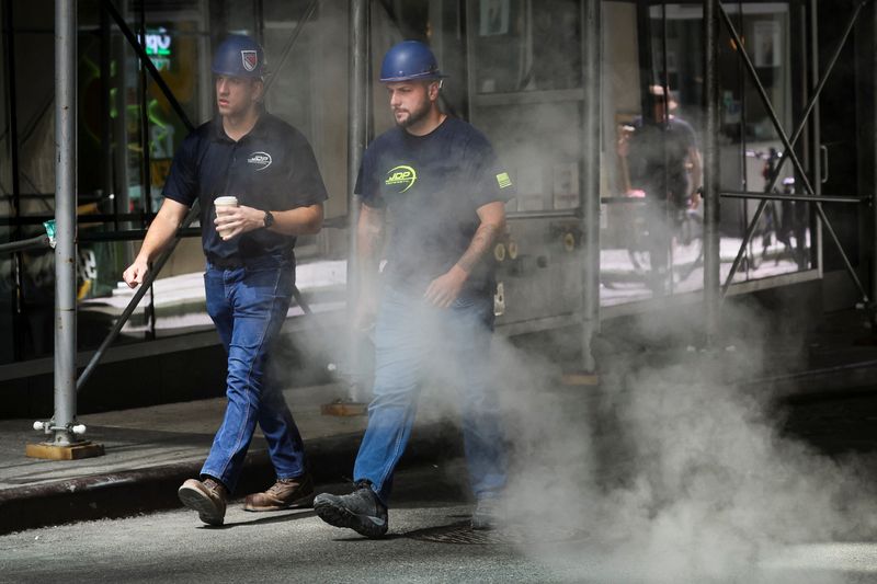 Workers walk through a cloud of steam during a heatwave in New York City, Tuesday. Across the United States, Americans have been enduring in some cases dangerously high heat that meteorologists say will last into next week.