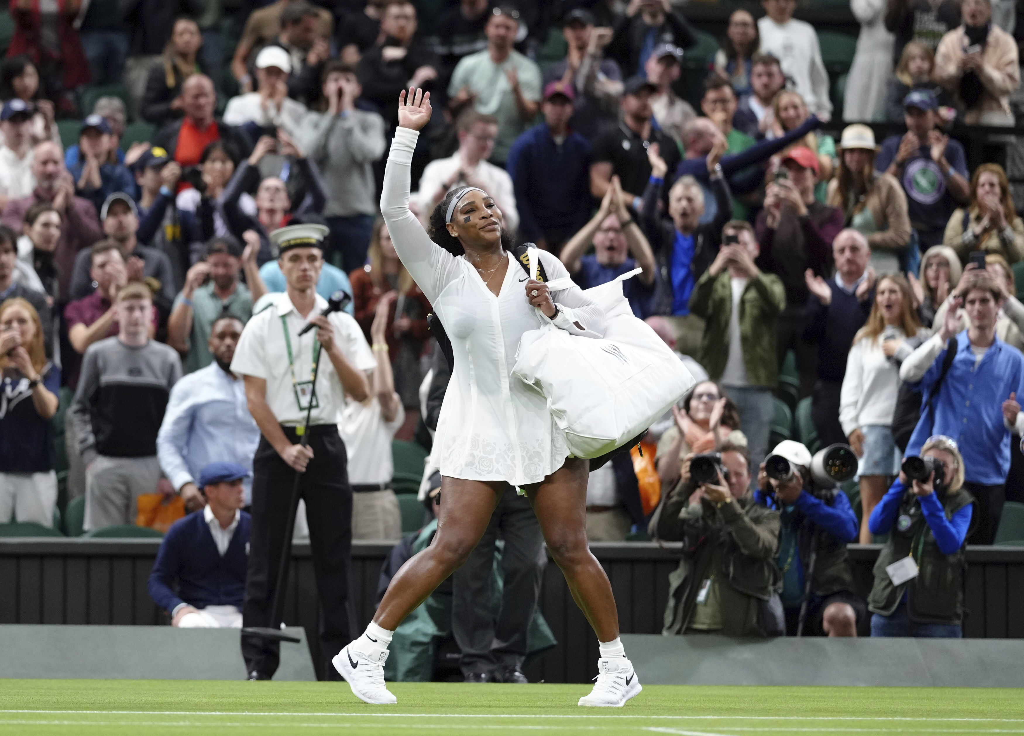 Serena Williams of the US waves as she leaves the court after losing to France's Harmony Tan in a first round women’s singles match on day two of the Wimbledon tennis championships in London, Tuesday, June 28, 2022. 