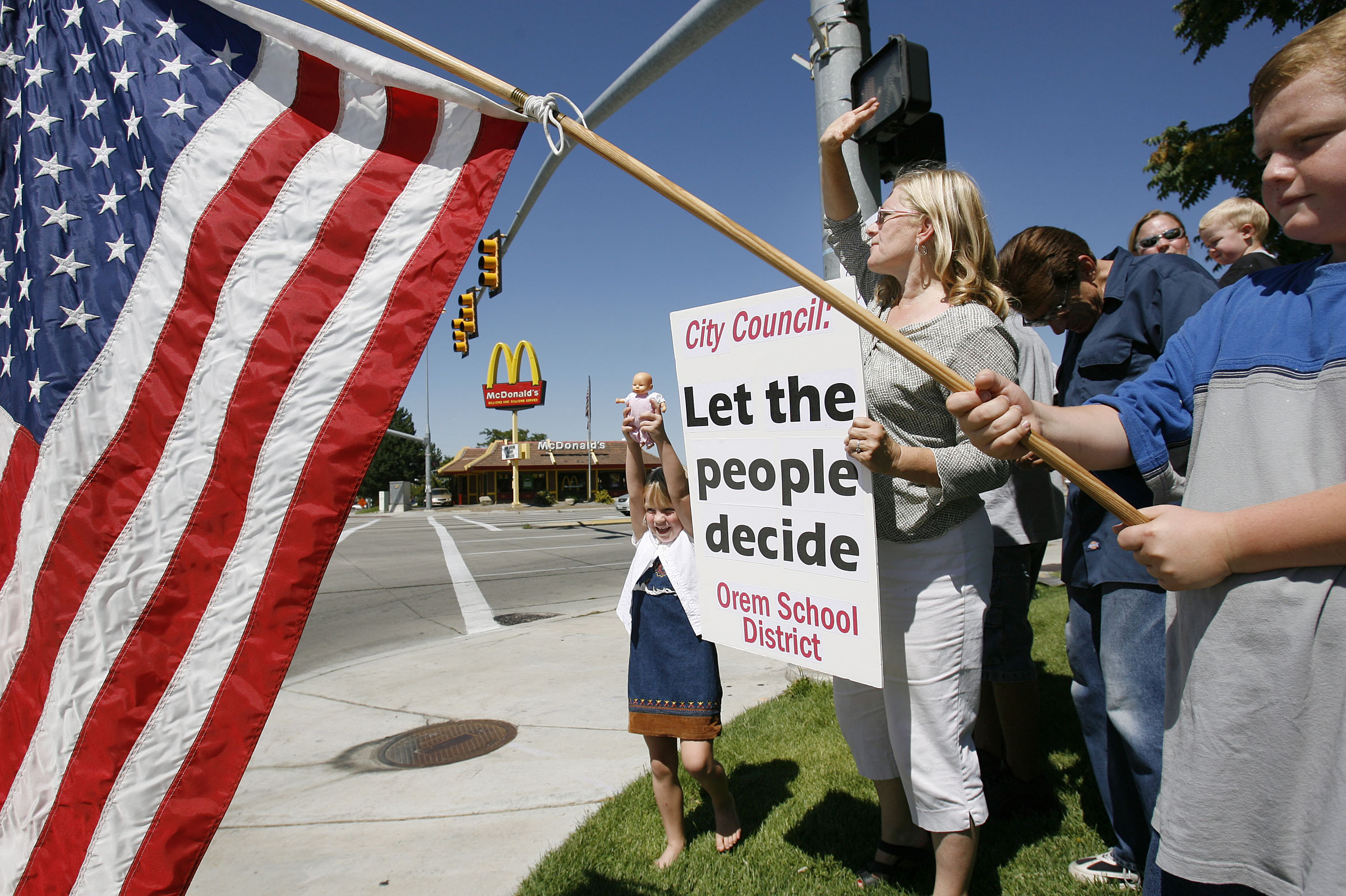 Laurie Lisonbee, center, and other supporters of Orem splitting from Alpine School District stand on State Street and Center Street in Orem with signs to convince the Orem City Council to put it on the ballot and let voters decide the fate of the school district on Aug. 21, 2006. The city of Orem has held two recent public meetings since a feasibility study made public last week found Orem splitting from Alpine School District to form its own school district would be viable in key areas, which piqued public interest.