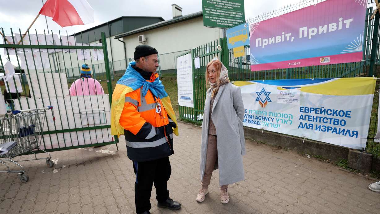 Volunteer Sasha wears a Ukrainian flag while talking with Anzhela Kumurxhi, a Ukrainian refugee from Mariupol, at the Ukrainian-Polish border in Medyka, Poland, on April 19. Almost 2 million Ukrainian refugees are now living in Russia, some of them forcibly removed in what officials in the war-torn country say is a war crime.