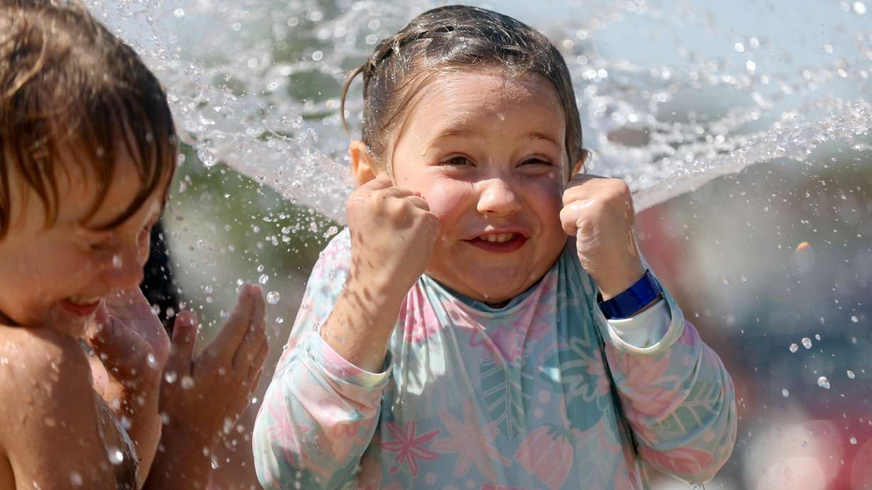 Samson Maurer and Mora Carter react as a fountain sprays them at the Draper City Splash Pad during a heat wave in Draper on Wednesday. Hot temperatures are expected across Utah heading into the Pioneer Day holiday weekend.