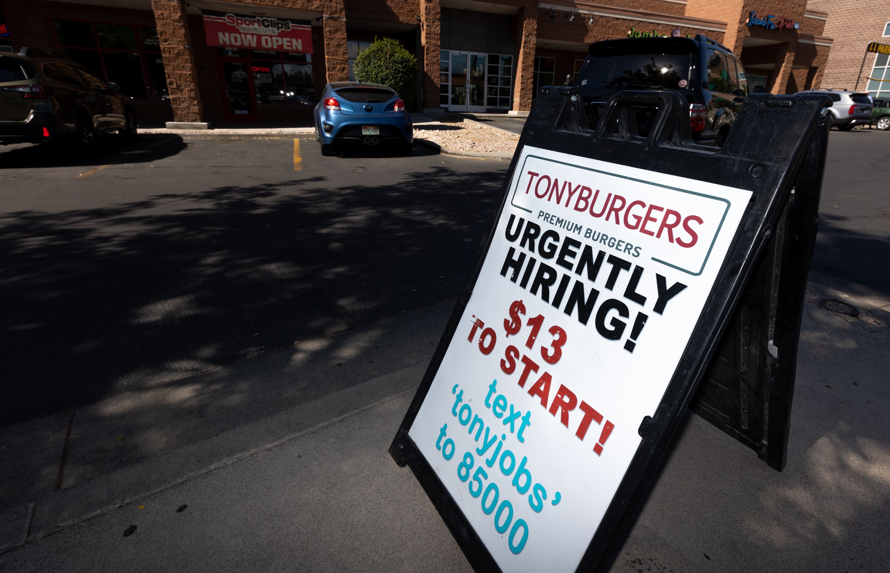 An “Urgently hiring” sign sits on the sidewalk in front of Tonyburgers in Salt Lake City on Wednesday. According to recent analysis, the current minimum wage is now at its lowest value since 1956.