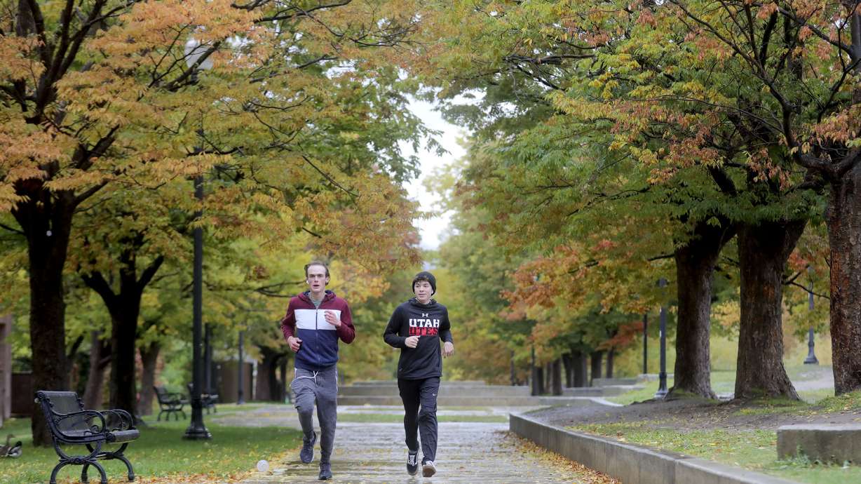 Ethan Hickey, left, and Nick Wilcox jog in the rain at Liberty Park in Salt Lake City on Oct. 19, 2021. The Salt Lake City Urban Forest Action Plan looks to increase the number of trees in the city.