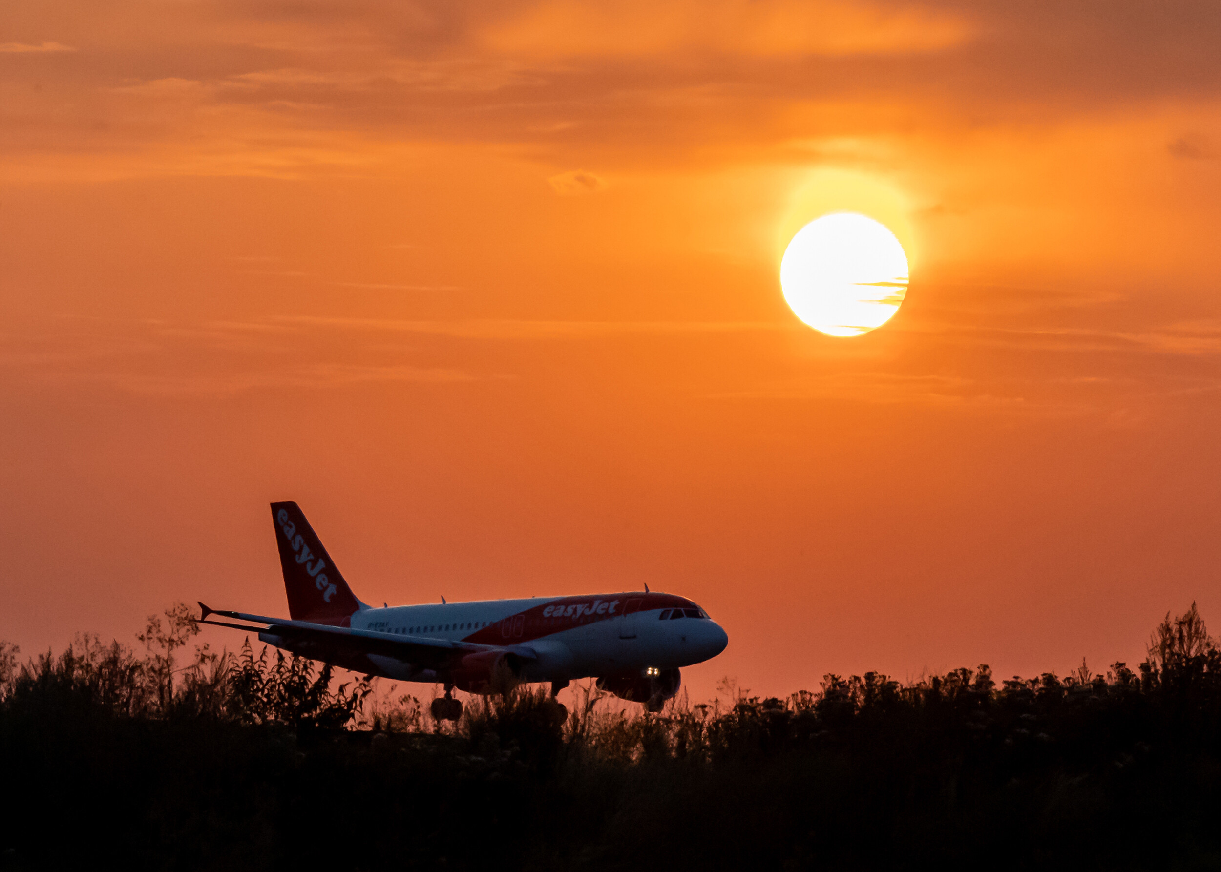 An Easy Jet plane lands during sunset at Luton Airport after a small section of the runway had lifted due to high temperatures on Monday, July 18.