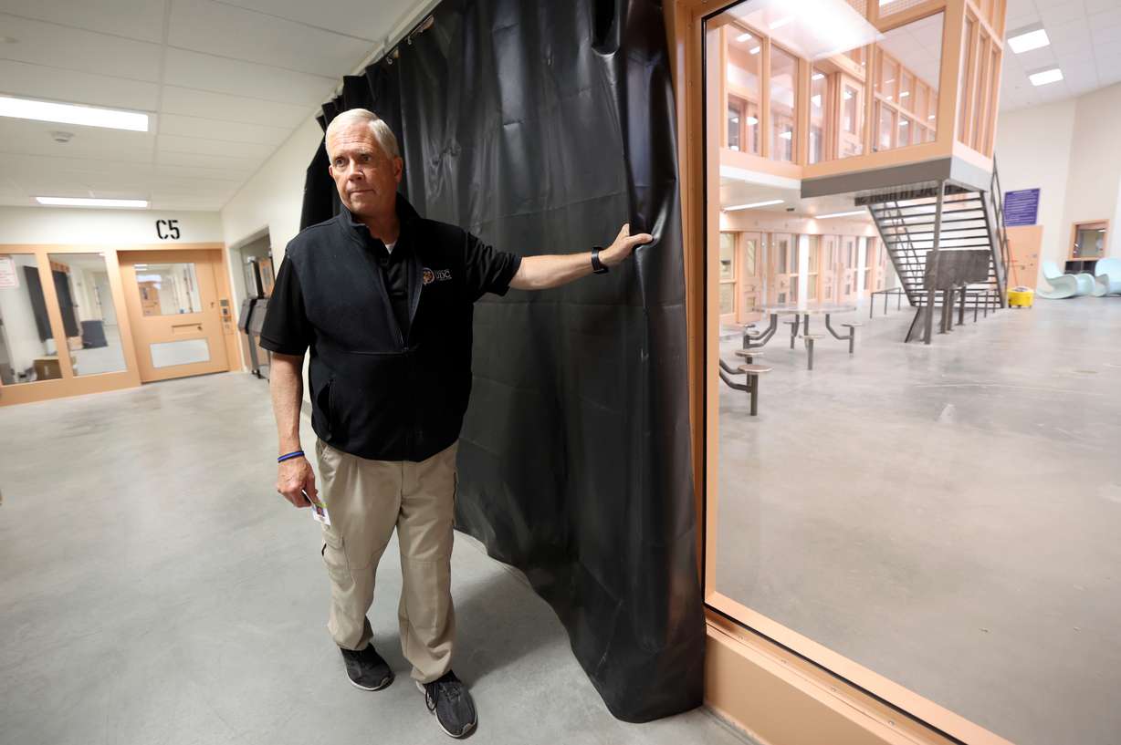 Steve Turley, Utah Department of Corrections special projects director, shows how a curtain will provide privacy for female inmates and create a visual barrier between males and females in the new Utah State Correctional Facility in Salt Lake City on Thursday, June 30.