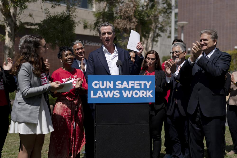 California Gov. Gavin Newsom, center, celebrates after singing a gun control law as he is surrounded by state officials including state Sen. Bob Hertzberg, right, state Sen. Anthony Portantino, second right, Attorney General Rob Bonta, third left, and gun violence survivors, Mia Tretta, and Arvis Jones, at Santa Monica College campus in Santa Monica, Calif., Friday. 