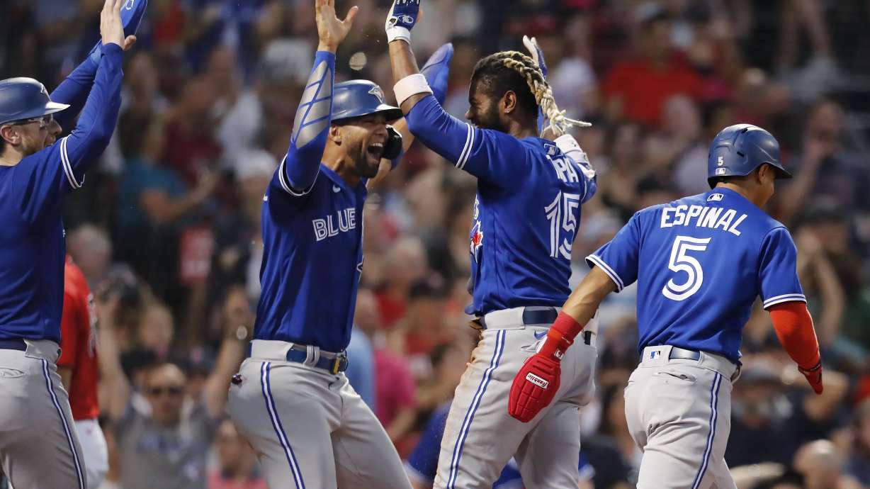 Toronto Blue Jays' Raimel Tapia (15) celebrates his inside-the-park grand slam that scored Lourdes Gurriel Jr., center left, Danny Jansen, left, and Santiago Espinal (5) during the third inning of the team's baseball game against the Boston Red Sox, Friday, July 22, 2022, in Boston.