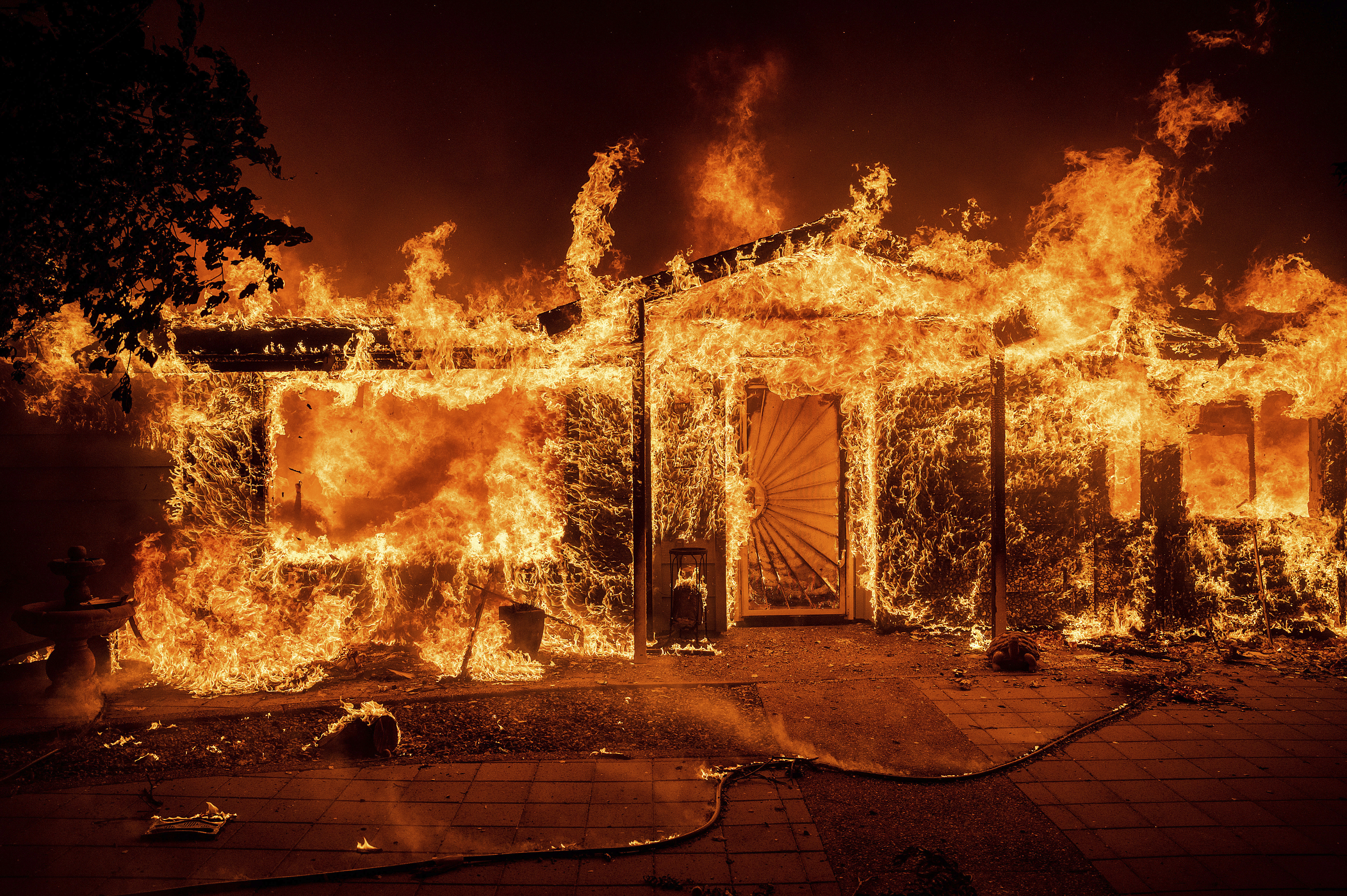 Flames consume a home on Triangle Rd. as the Oak Fire burns in Mariposa County, Calif., on July 23.