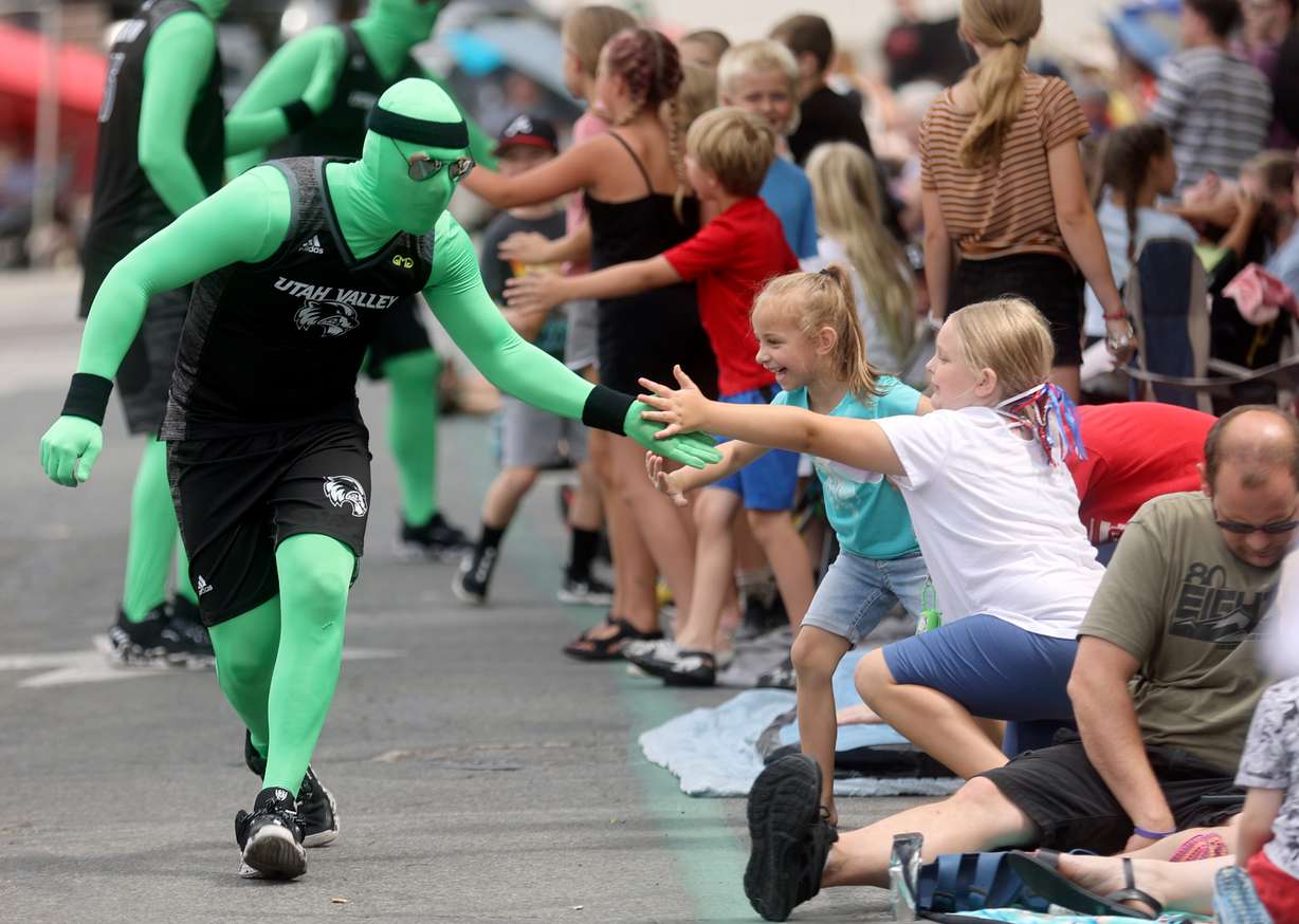 Children high-five the Utah Valley University float participants dressed in green during the '47 Days Parade in Salt Lake City on Saturday.