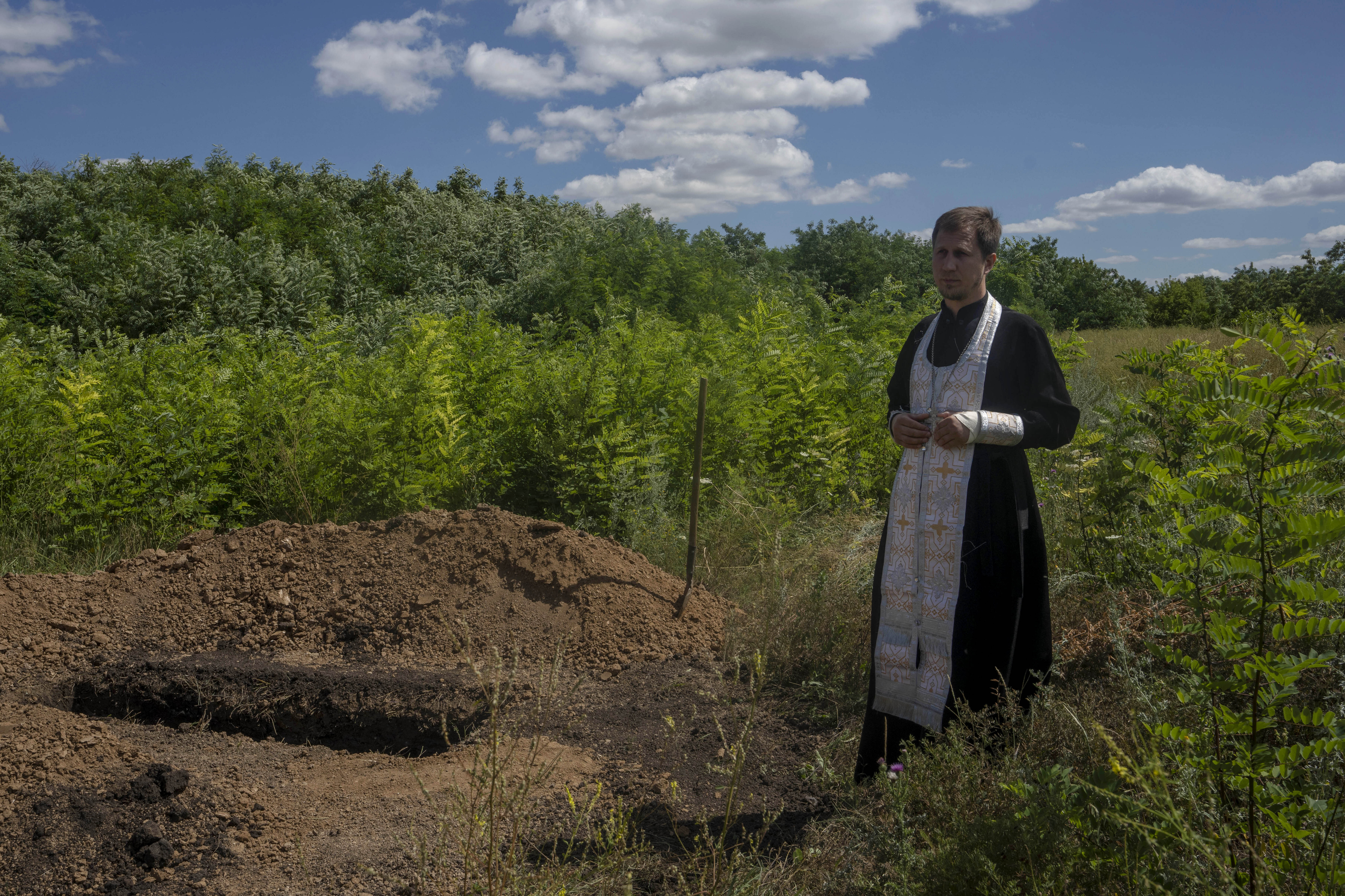A priest prepares to pray over the lifeless body of 35-year-old Anna Protsenko, who was killed in a Russian rocket attack, before her burial, during her funeral procession, on the outskirts of Pokrovsk, eastern Ukraine, July 18. Protsenko was killed two days after coming home. She had done what authorities wanted, evacuating eastern Ukraine's Donetsk region as Russian forces move closer, but starting a new life elsewhere was uncomfortable and expensive.