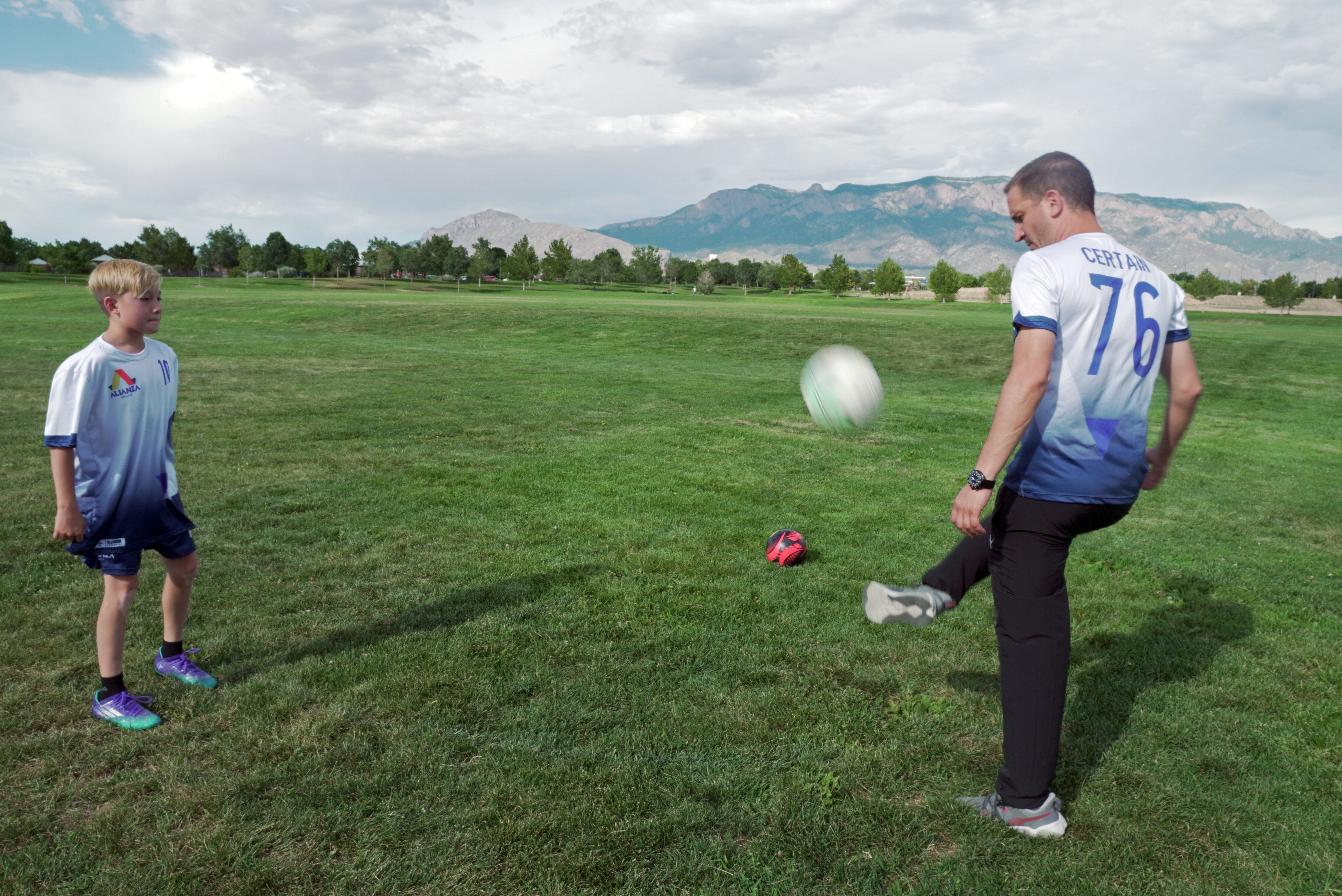 In this photo provided by Vince Trujillo, David Certain, right, plays soccer with his son Nico in Albuquerque, New Mexico, Thursday, July 21, 2022. Certain, a Colombian soccer lover who came to the United States as a political refugee, has united several former professional Colombian soccer players to join him in creating a youth sports education program in New Mexico in July 2022. 