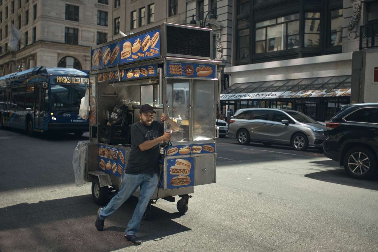 A man pushes his hotdog mobile shop along Fifth Avenue on Wednesday in New York. The Federal Reserve raised its benchmark interest rate by a hefty three-quarters of a point for a second straight time in its most aggressive drive in three decades to tame high inflation.