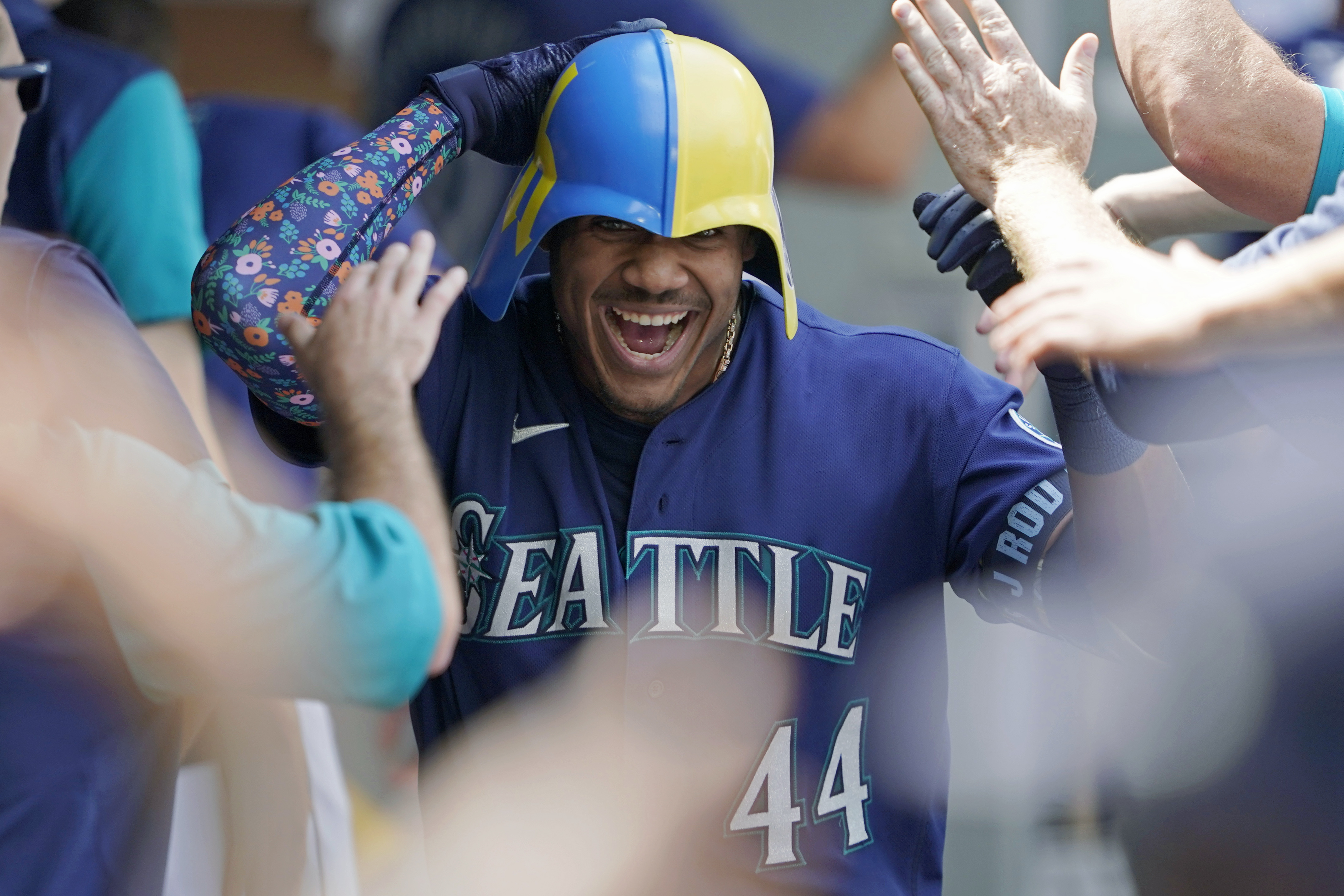 Seattle Mariners' Julio Rodriguez wears a helmet as he is greeted in the dugout after his three-run home run against the Texas Rangers during the seventh inning of a baseball game Wednesday, July 27, 2022, in Seattle. 
