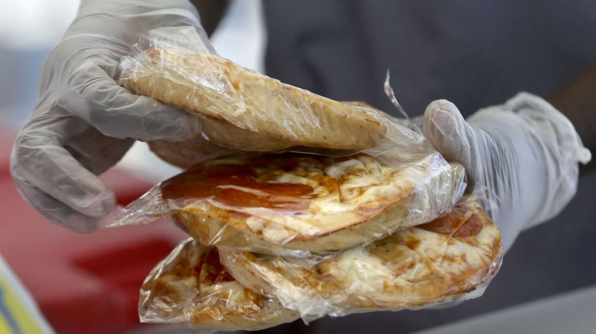Nutrition technician Besie Sabit puts slices of pizza into bagged lunches outside of Edison Elementary School in Salt Lake City on Sept. 28, 2020. Utah Attorney General Sean D. Reyes on Wednesday joined 22 other attorneys general in a lawsuit against the Biden Administration for threatening to withhold nutritional assistance for schools that don't follow new sex discrimination programs.