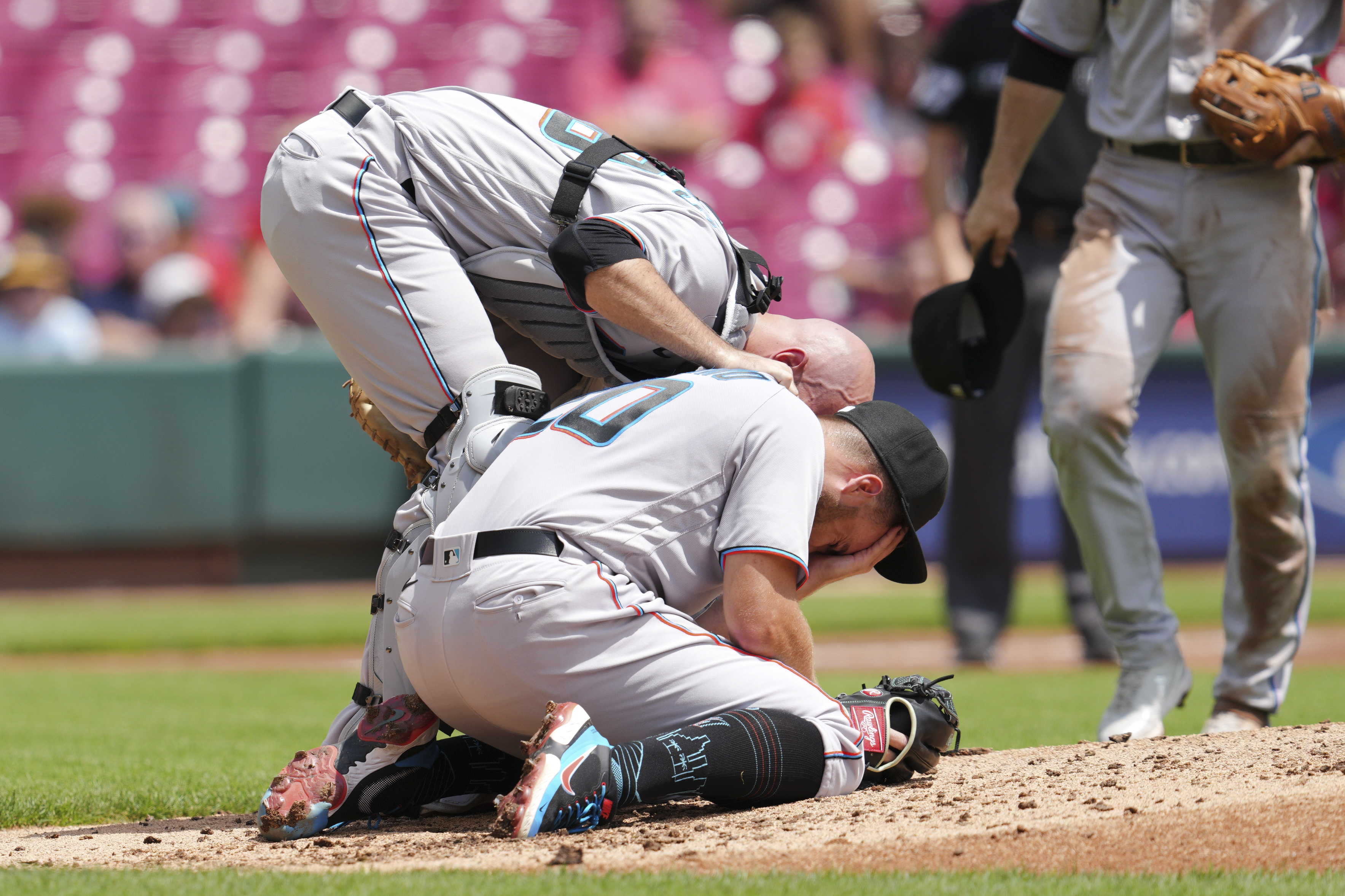 Miami Marlins catcher Jacob Stallings, left, checks on starting pitcher Daniel Castano after he was hit by a line drive by Cincinnati Reds' Donovan Solano during the first inning of a baseball game Thursday, July 28, 2022, in Cincinnati.