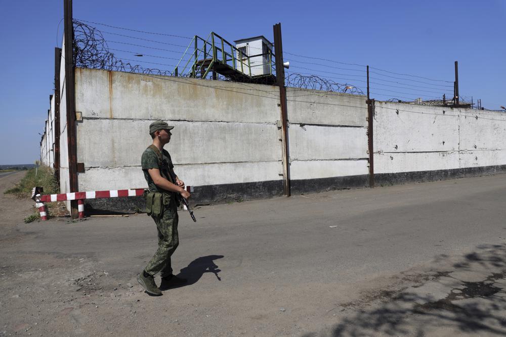 A soldier stand guard next to a wall of a prison in Olenivka, in an area controlled by Russian-backed separatist forces, eastern Ukraine, Friday. Russia and Ukraine accused each other Friday of shelling a prison in a separatist region of eastern Ukraine, an attack that reportedly killed dozens of Ukrainian military prisoners who were captured after the fall of a southern port city of Mariupol in May.