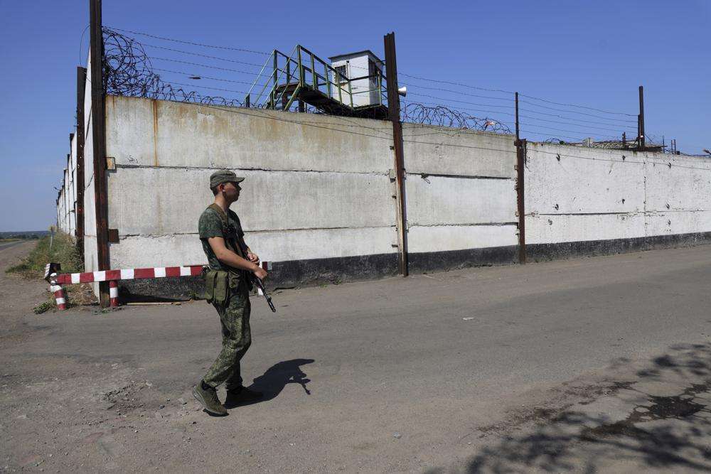 A soldier stand guard next to a wall of a prison in Olenivka, in an area controlled by Russian-backed separatist forces, eastern Ukraine, Friday. Russia and Ukraine accused each other Friday of shelling a prison in a separatist region of eastern Ukraine, an attack that reportedly killed dozens of Ukrainian military prisoners who were captured after the fall of a southern port city of Mariupol in May.