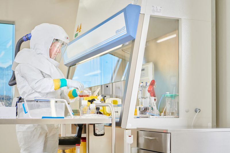 A staff member of Spiez Laboratory in a BSL-3 lab removes a cell culture bottle infected with viruses from the safety cabinet and places it in a transport box in a bio-containment facility that is available to the World Health Organization as a repository for SARS-CoV-2 viruses or other pathogens with epidemic or pandemic potential, in this handout picture taken June 1, in Spiez, Switzerland.  