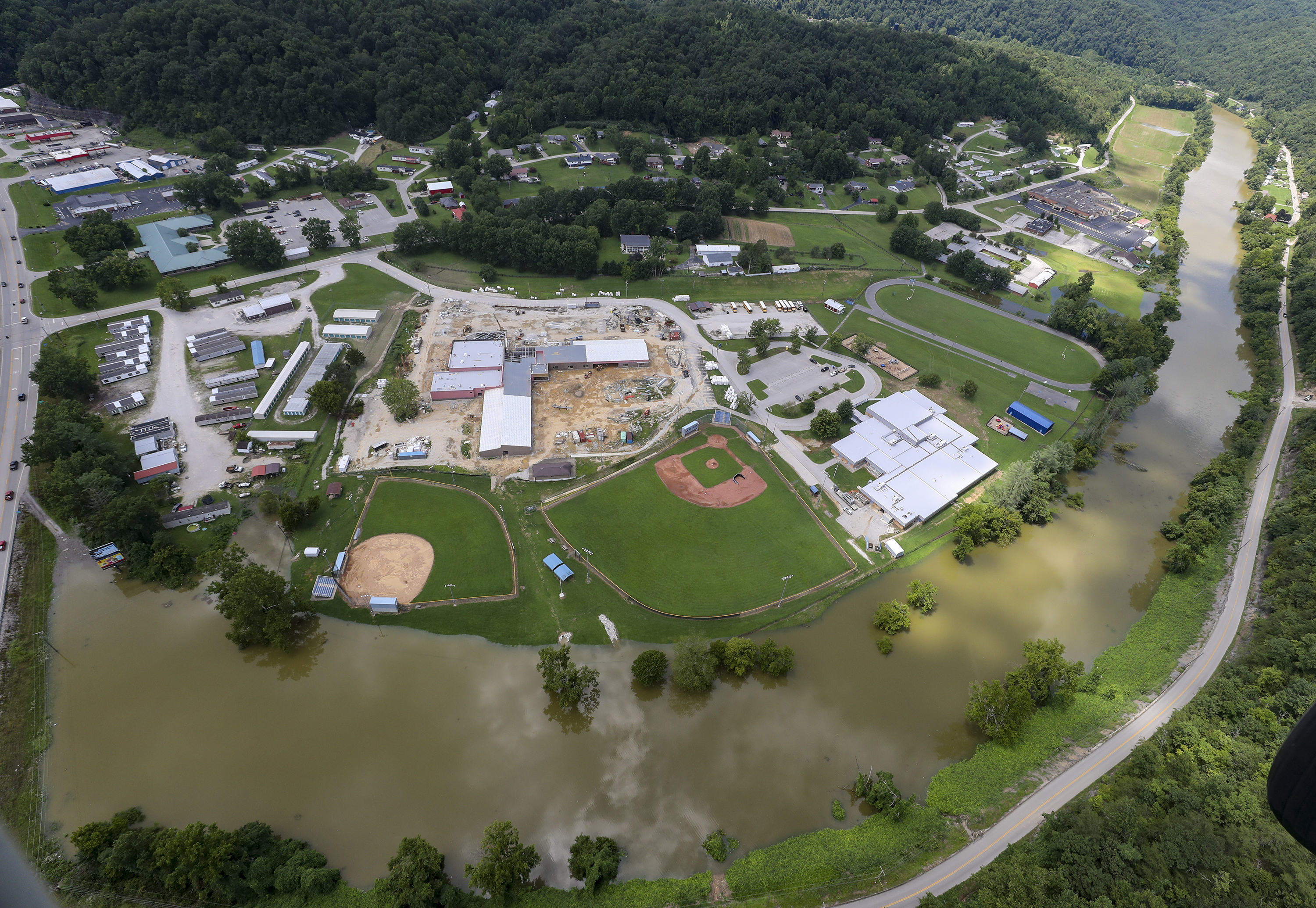 In this aerial image, the river is still high around the homes in Breathitt County, Ky., on Saturday. Recovery has begun in many of the narrow hollers after historic rains flooded many areas of Eastern Kentucky killing more at least two dozen people. A layer of mud from the retreating waters covers many cars and homes. 