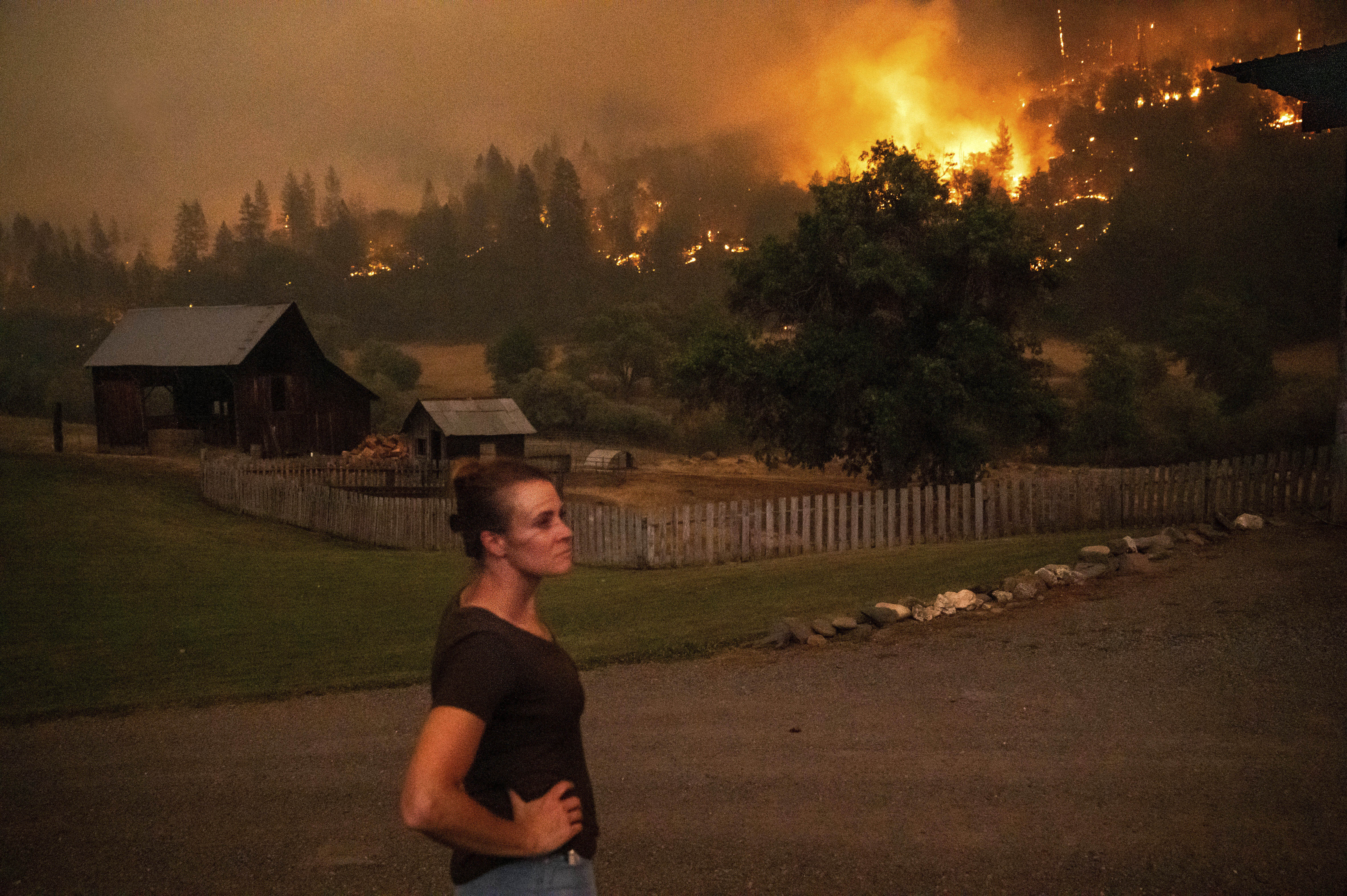 Angela Crawford watches as a wildfire called the McKinney fire burns a hillside above her home in Klamath National Forest, Calif., on Saturday. Crawford and her husband stayed, as other residents evacuated, to defend their home from the fire.