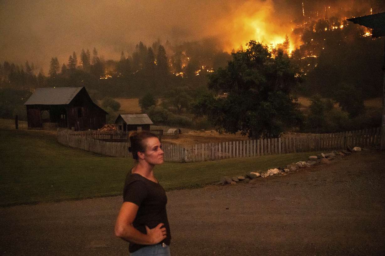 Angela Crawford watches as a wildfire called the McKinney fire burns a hillside above her home in Klamath National Forest, Calif., on Saturday. Crawford and her husband stayed, as other residents evacuated, to defend their home from the fire.