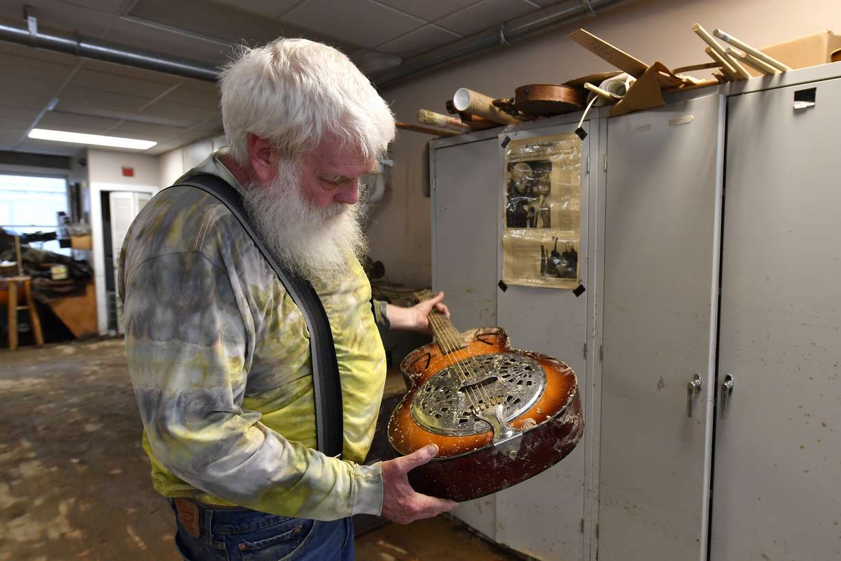Paul Williams inspects the damage to a dobro guitar damaged by floodwaters from Troublesome Creek at the Applachian School of Luthery workshop and museum in Hindman, Ky., Sunday.