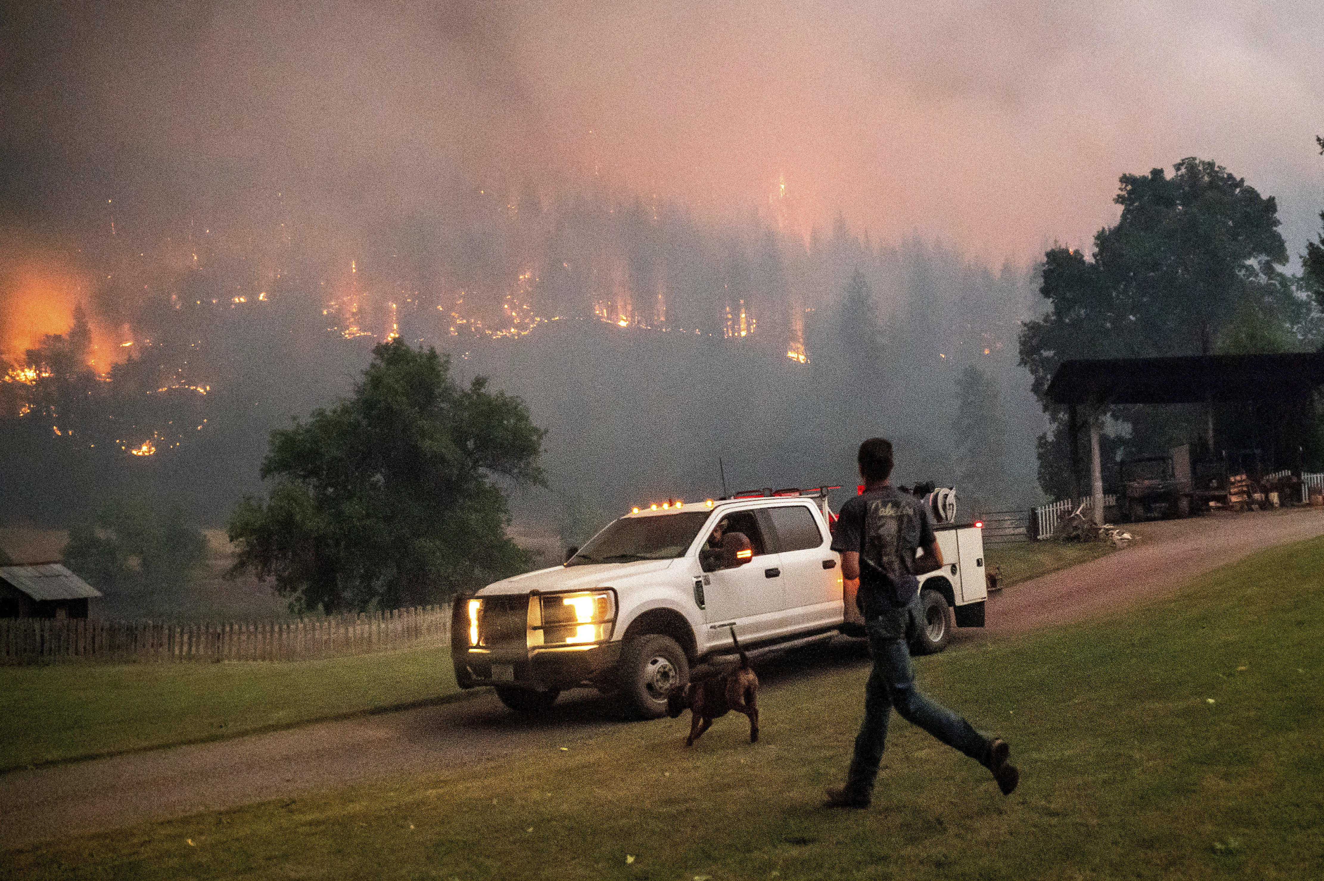 A man runs to a truck as a wildfire called the McKinney fire burns in Klamath National Forest, Calif., on Saturday.