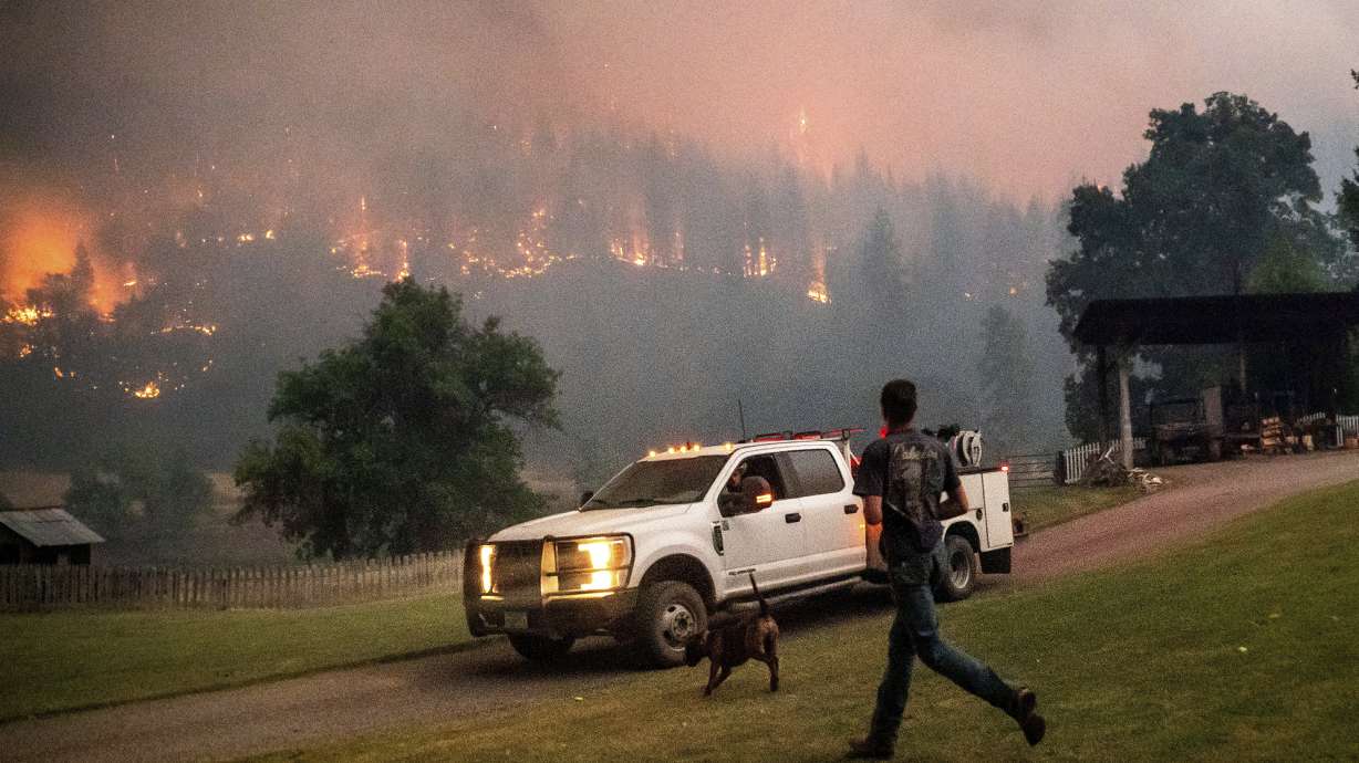 A man runs to a truck as a wildfire called the McKinney fire burns in Klamath National Forest, Calif., on Saturday.