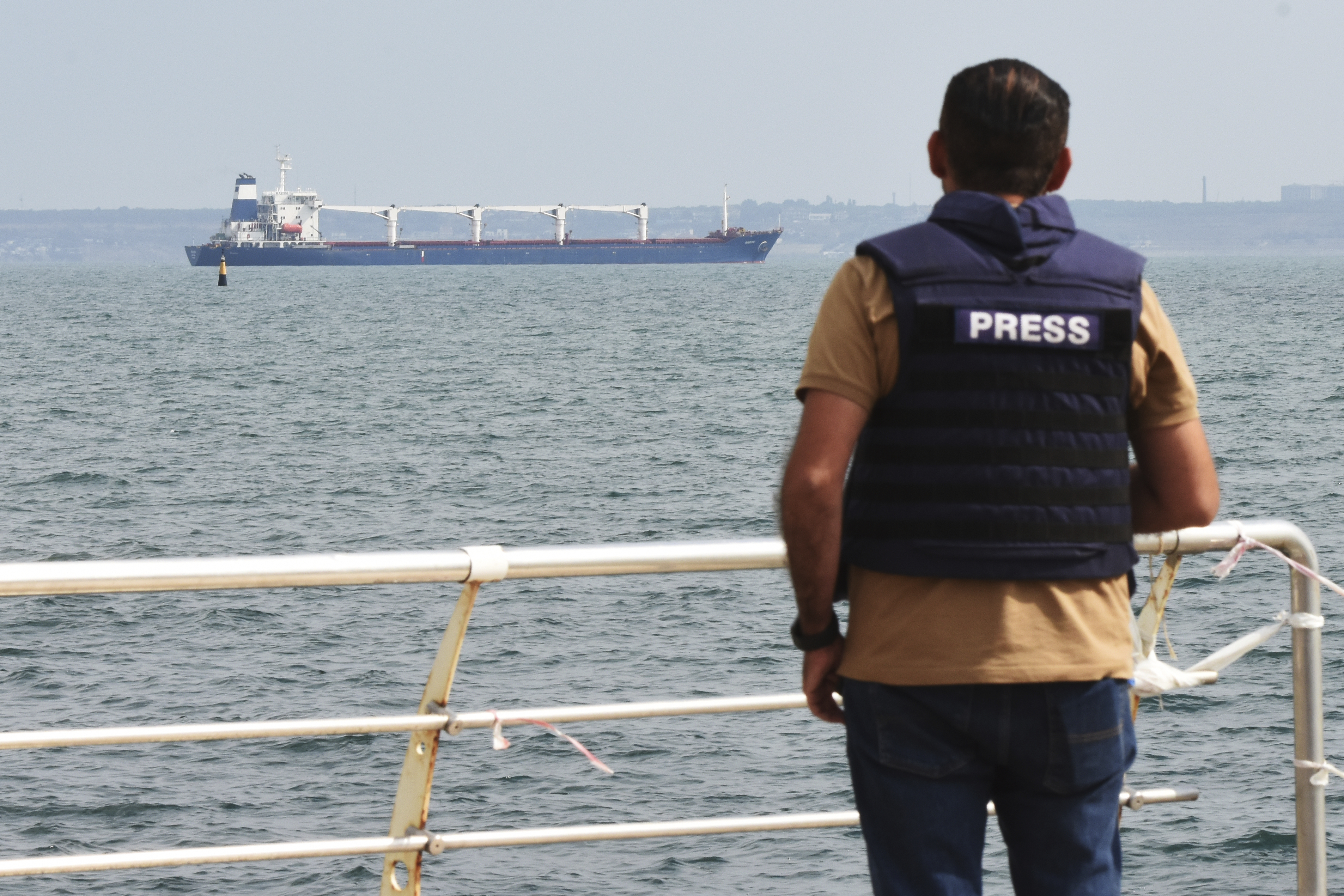 A journalist watches as the bulk carrier Razoni starts its way from the port in Odesa, Ukraine, Monday. According to Ukraine's Ministry of Infrastructure, the ship under Sierra Leone's flag is carrying 26 thousand tons of Ukrainian corn to Lebanon. The first ship carrying Ukrainian grain set off from the port of Odesa on Monday under an internationally brokered deal and is expected to reach Istanbul on Tuesday, where it will be inspected, before being allowed to proceed.
