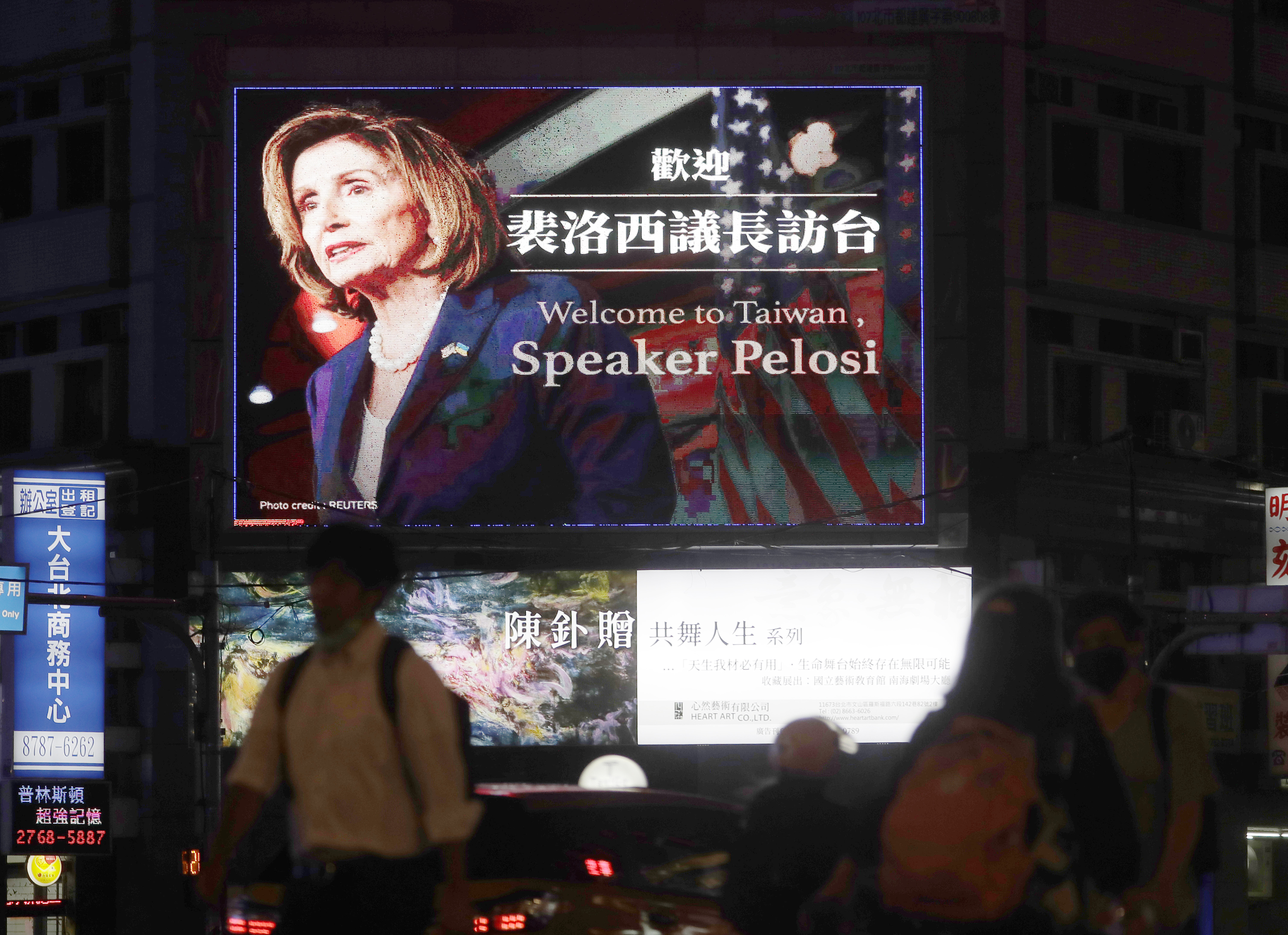 People walk past a billboard welcoming U.S. House Speaker Nancy Pelosi, in Taipei, Taiwan, Tuesday. Pelosi arrived in Taiwan on Tuesday on a visit that could significantly escalate tensions with Beijing, which claims the self-ruled island as its own territory.