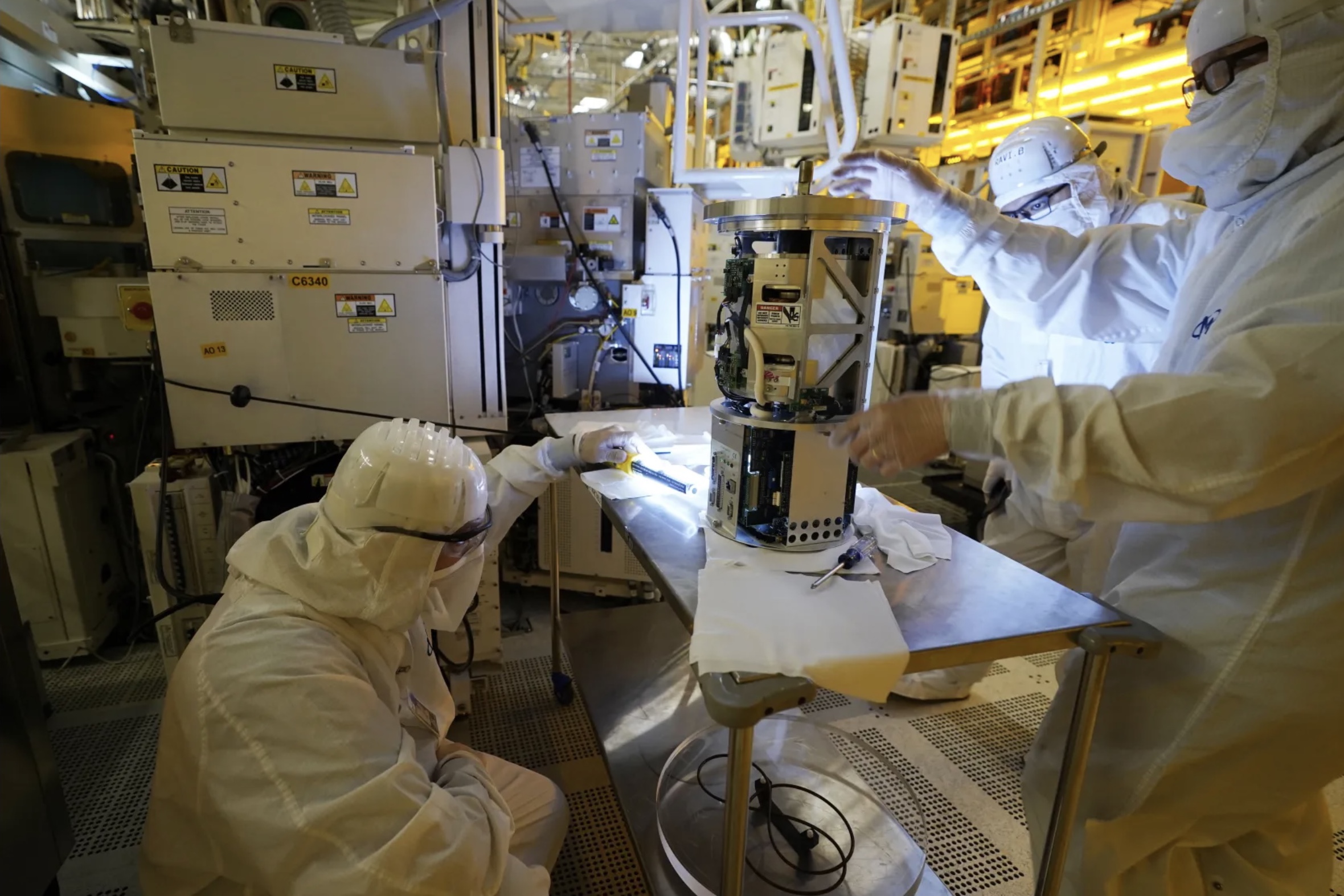 Technicians inspect a piece of equipment during a tour of the Micron Technology automotive chip manufacturing plant on Feb. 11 in Manassas, Virginia. A bill to boost semiconductor production in the United States is made its way through the Senate and is a top priority of the Biden administration.