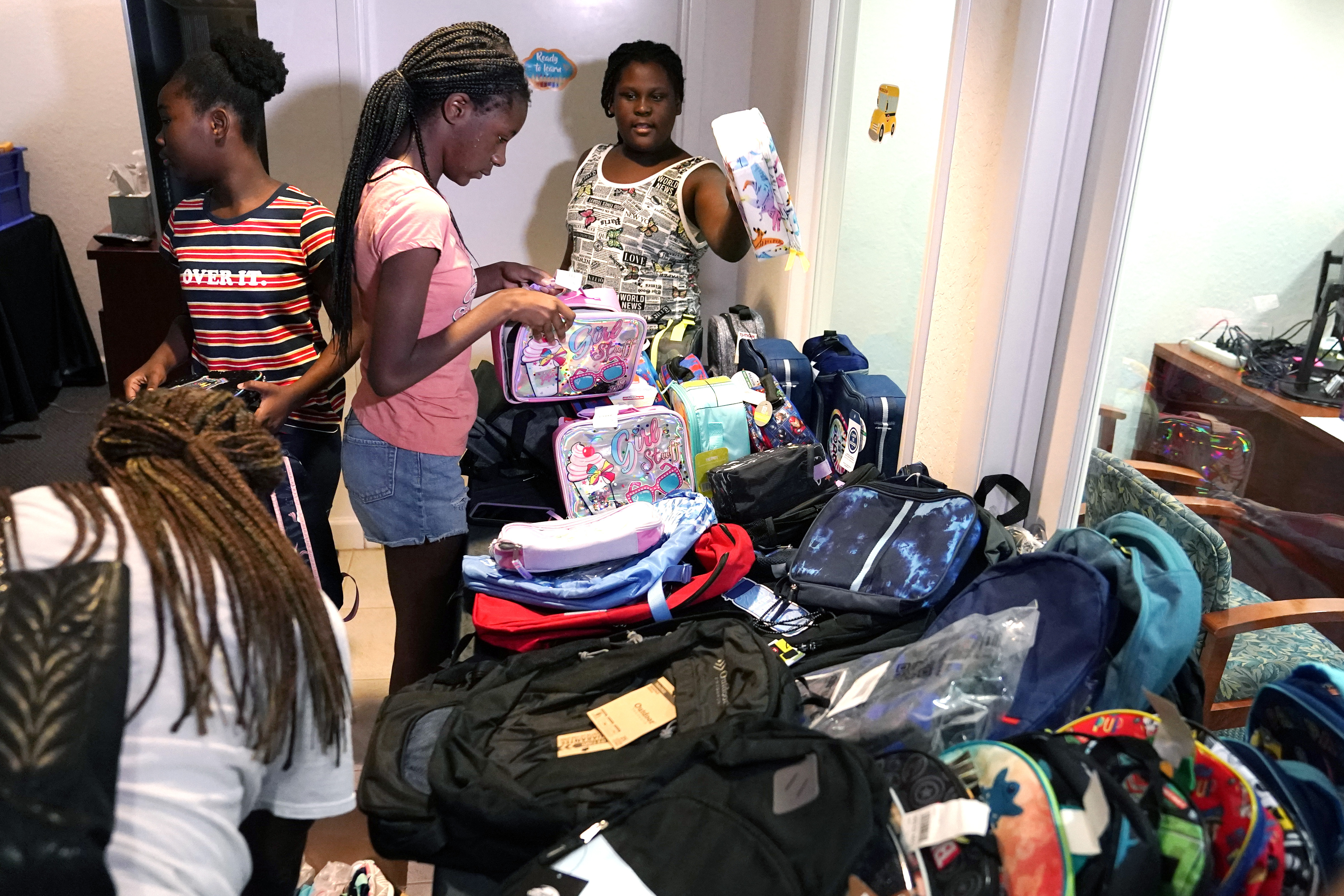 Chrishauna Hurst, 12, center, and Aaliyah Floyd, 10, right, select lunch boxes at the annual Back to School Distribution Day at The Pantry, Friday, in Fort Lauderdale, Fla. The Pantry works with grandparents who are the primary caregivers for their grandchildren, offering free backpacks, lunch boxes, school supplies and sneakers.