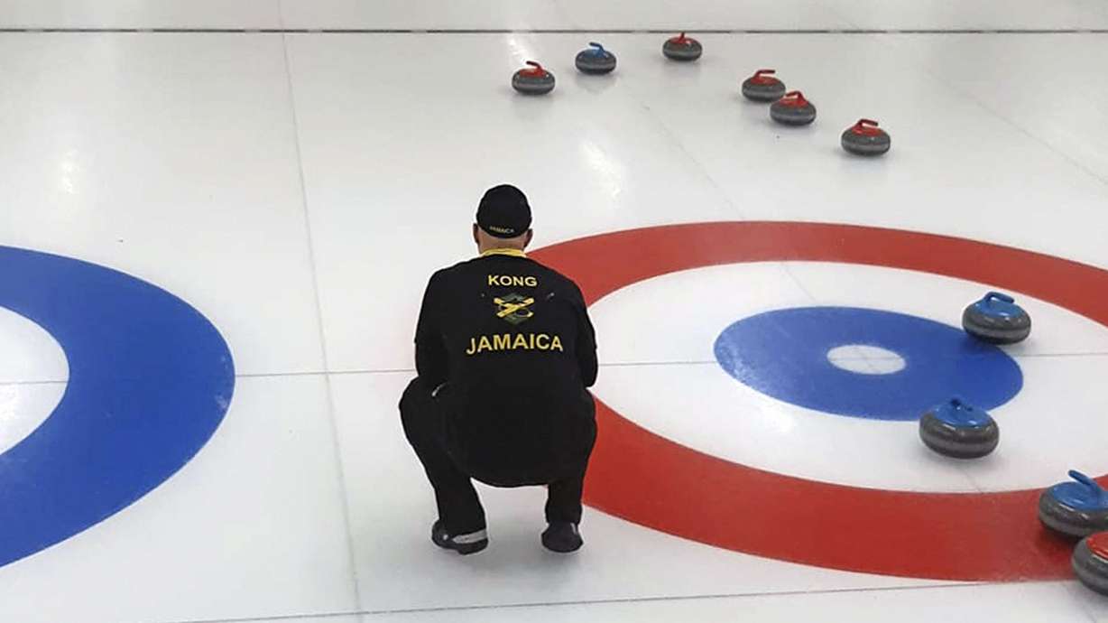 In this photo provided by Curling Jamaica, Jamaica's Ben Kong looks out at the sheet during a practice game against Hong Kong on Saturday, April 2, 2022, at the Unionville Curling Club in Markham, Ontario, Canada. The Jamaican curlers are sliding into the footsteps of the bobsledders that brought the tropical island nation to the Winter Olympics and became an international sensation.