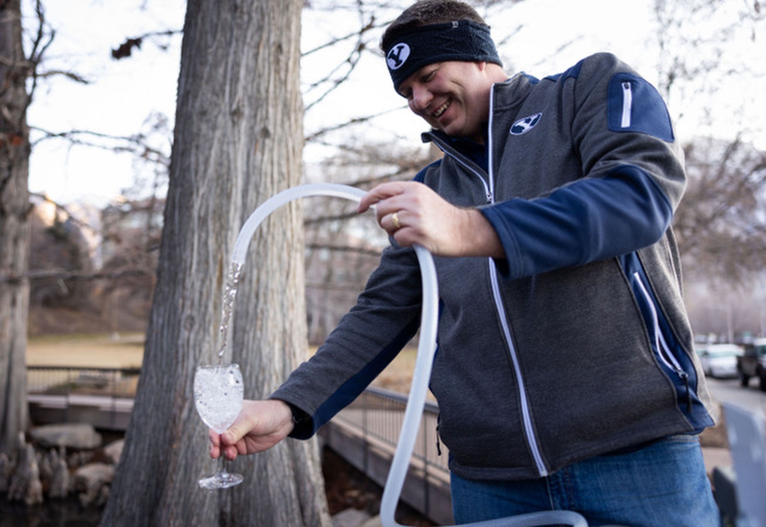 A BYU engineering student fills up a glass of filtered water after cleaning it through new water filtration device at the duck pond south of campus in Provo on Feb. 8.