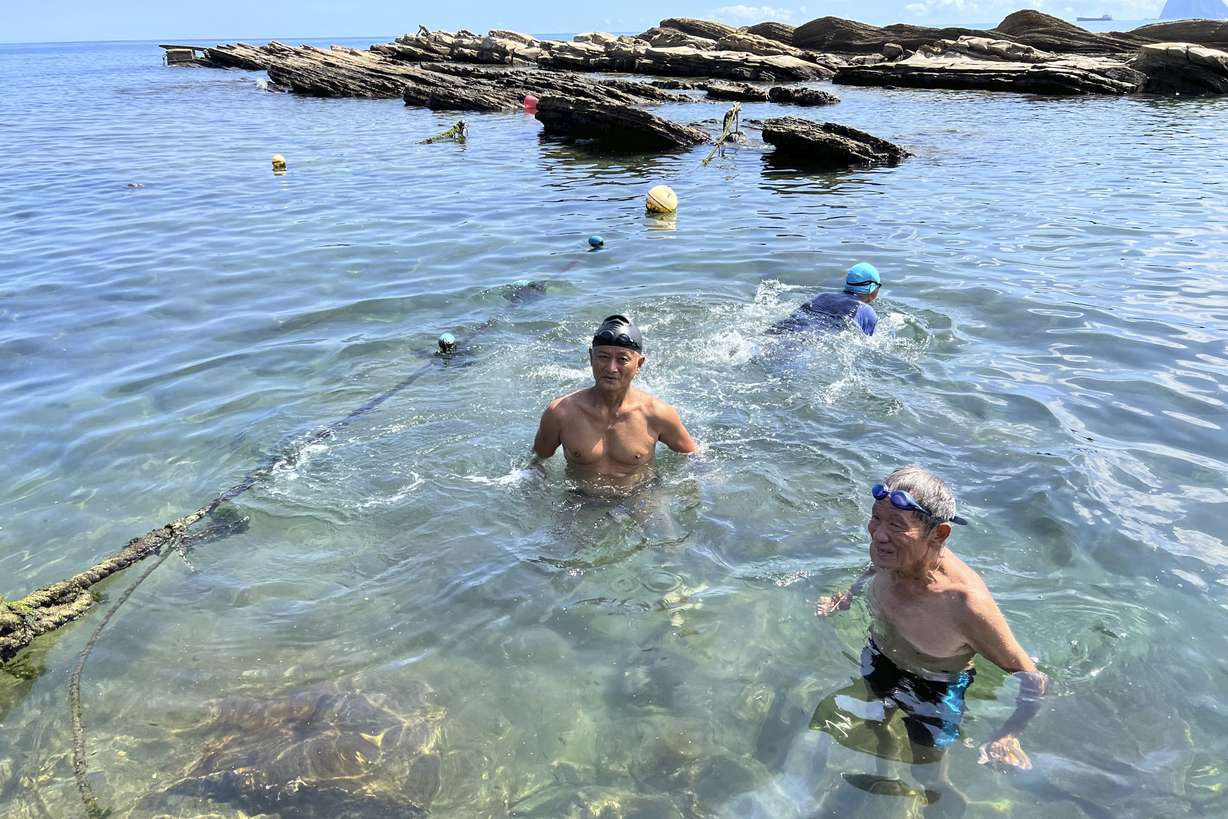 Residents swim along the coast Keelung city in Taiwan, Thursday. China is staging live-fire military drills in six self-declared zones surrounding Taiwan in response to a visit by U.S. House Speaker Nancy Pelosi to the island Beijing claims as its own territory.