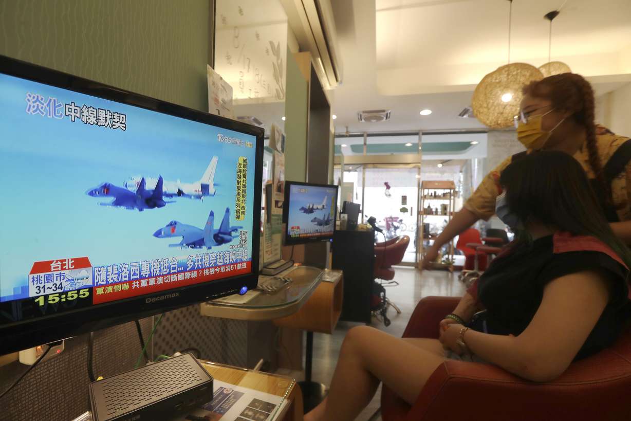 A customer and a staff member watch a news report on the recent tensions between China and Taiwan, at a beauty salon in Taipei, Taiwan, Thursday.