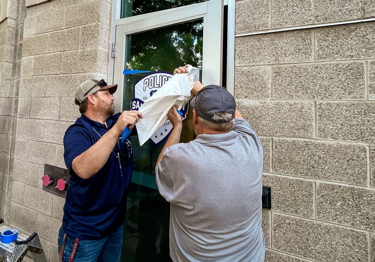 Salt Lake City employees place a Salt Lake City Police Department decal on the door of a new police substation at Smith's Ballpark Thursday morning.