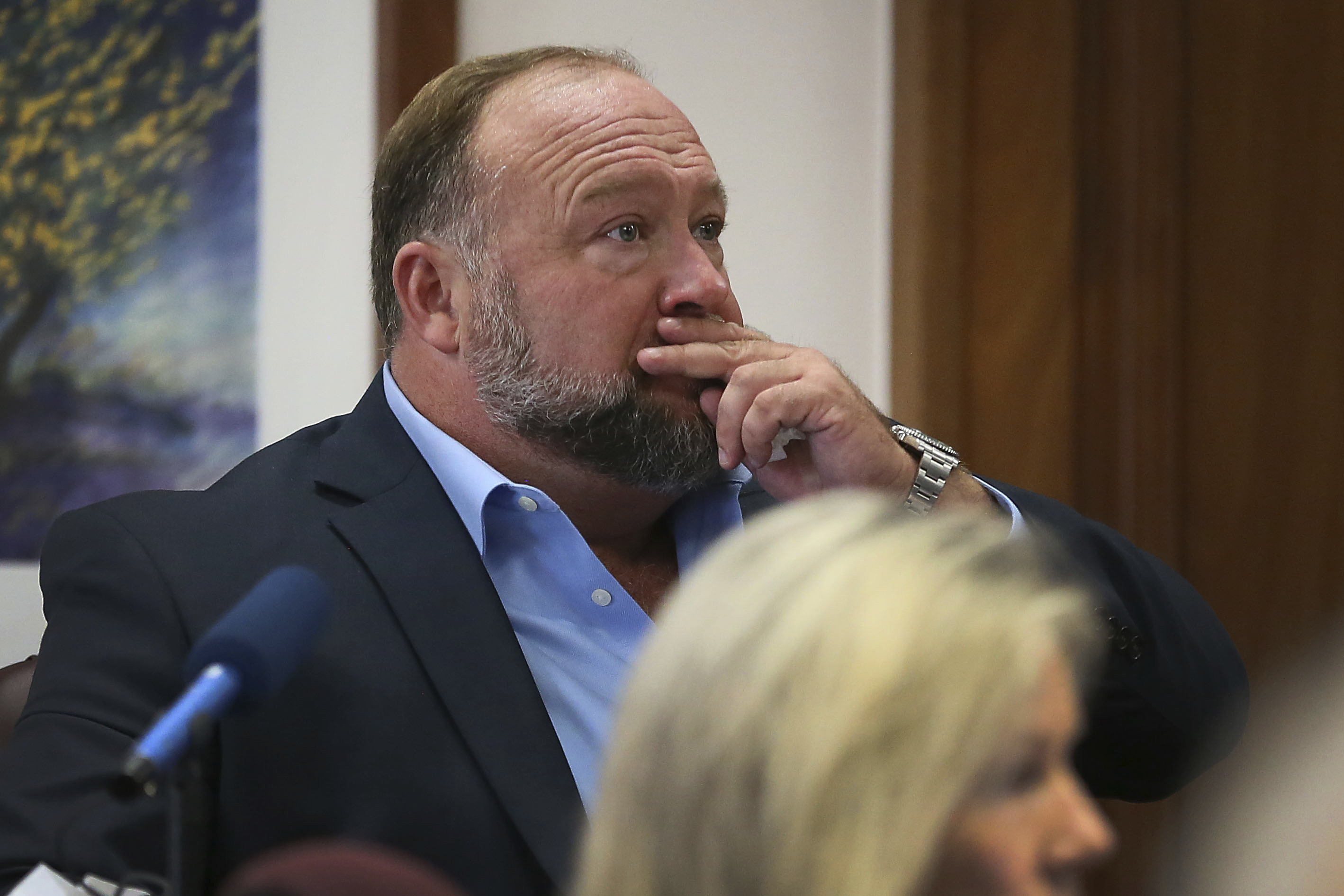 Alex Jones attempts to answer questions about his text messages asked by Mark Bankston, lawyer for Neil Heslin and Scarlett Lewis, during trial at the Travis County Courthouse in Austin, Wednesday. A Texas jury has ordered Jones to pay more than $4 million in compensatory damages to the parents of a 6-year-old boy who was killed in the 2012 Sandy Hook Elementary School massacre. 