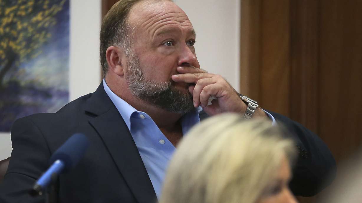 Alex Jones attempts to answer questions about his text messages asked by Mark Bankston, lawyer for Neil Heslin and Scarlett Lewis, during trial at the Travis County Courthouse in Austin, Wednesday. A Texas jury has ordered Jones to pay more than $4 million in compensatory damages to the parents of a 6-year-old boy who was killed in the 2012 Sandy Hook Elementary School massacre.