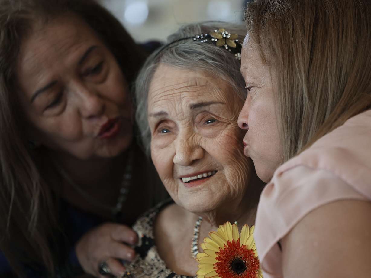 Telesila Castro, 107, is kissed by her daughters, Thalia Castro, left, and Mercy Viteri, at the 34th annual Centenarian Celebration at the Viridian Event Center in West Jordan on Thursday.
