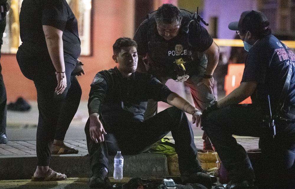 Police officer Ramon Perez is treated for shock after an SUV drove through the parade route of the Intertribal Ceremonial Centennial Celebration in Gallup, New Mexico, Thursday. Police arrested three people who were in a large SUV that drove through a Native American celebration in New Mexico, causing multiple injuries along a parade route crowded with families.