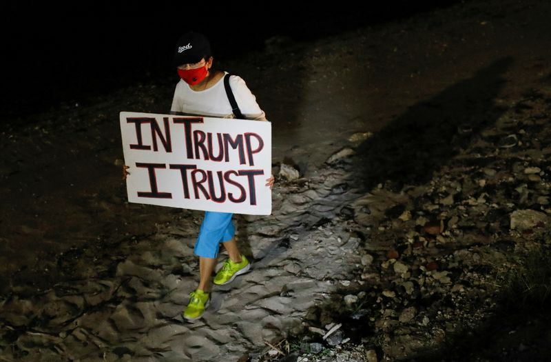 A person holds a sign as supporters of former U.S. President Donald Trump stand outside his Mar-a-Lago home after Trump said that FBI agents raided it, in Palm Beach, Florida, Monday.