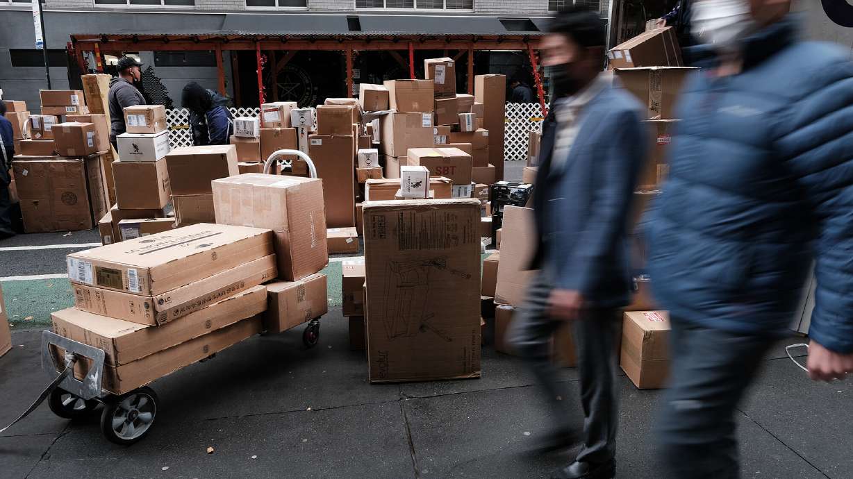 Dozens of packages are lined up along a Manhattan street as a FedEx truck makes deliveries on Dec. 6, 2021, in New York City. Online prices declined by 1% year-over-year in July, according to a report released Tuesday by Adobe.