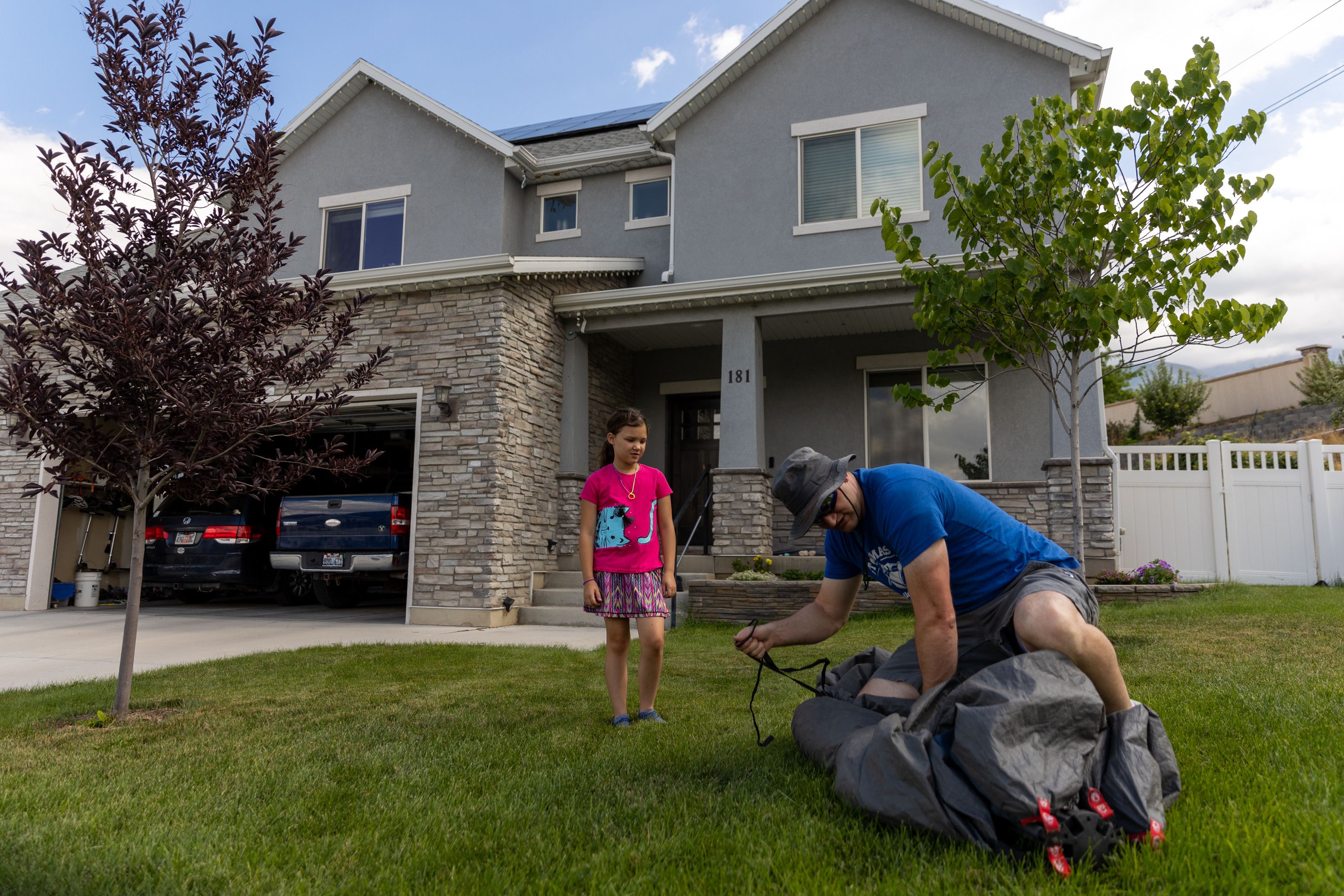 Ruth Cox, 9, helps her father, Seth Cox, roll up a tent that was left out to dry in front of their house in Lindon on Saturday. Rising property values in Utah have led to property tax hikes as well.